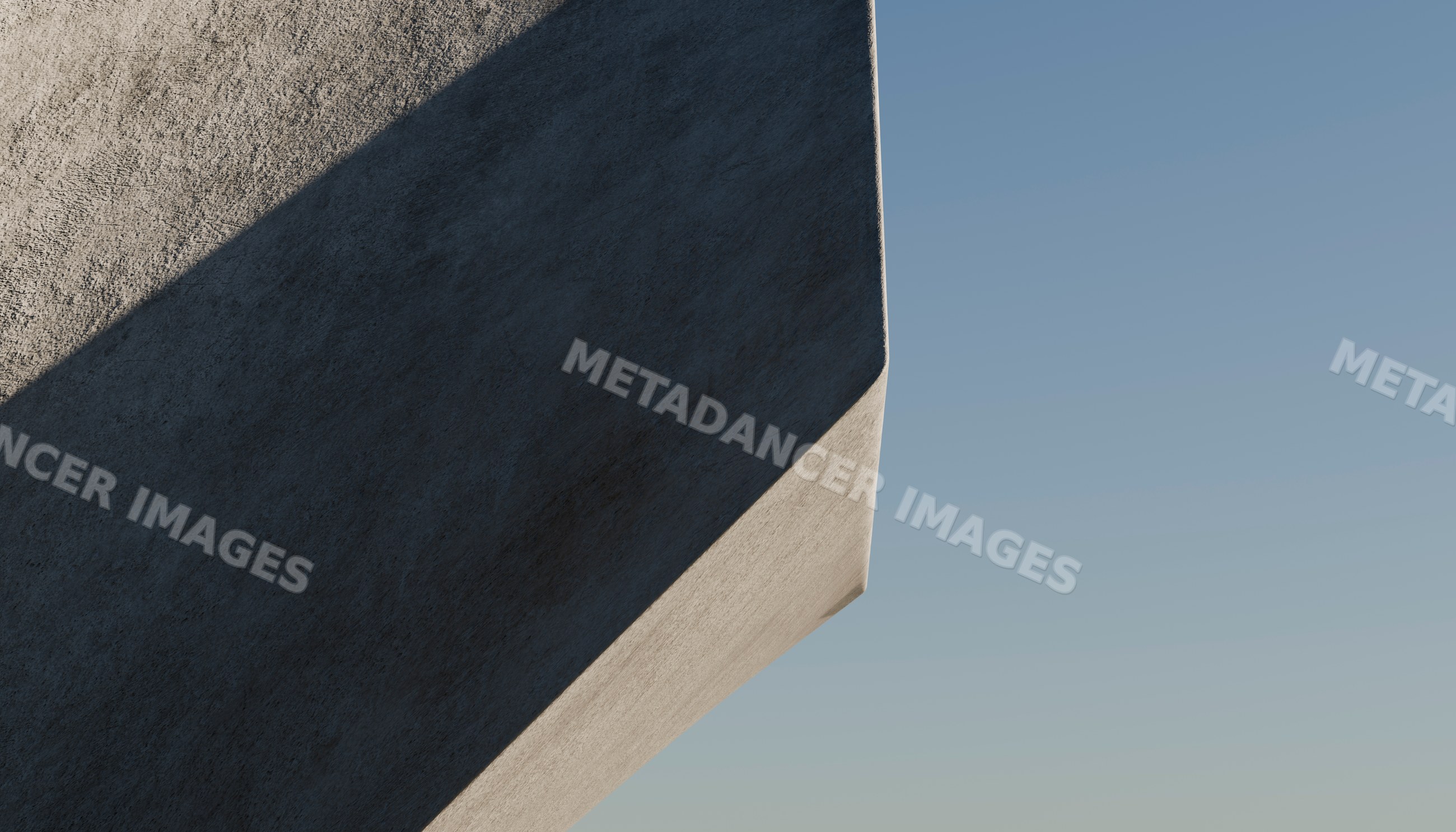 Close-up of a concrete building corner casting shadow under blue sky