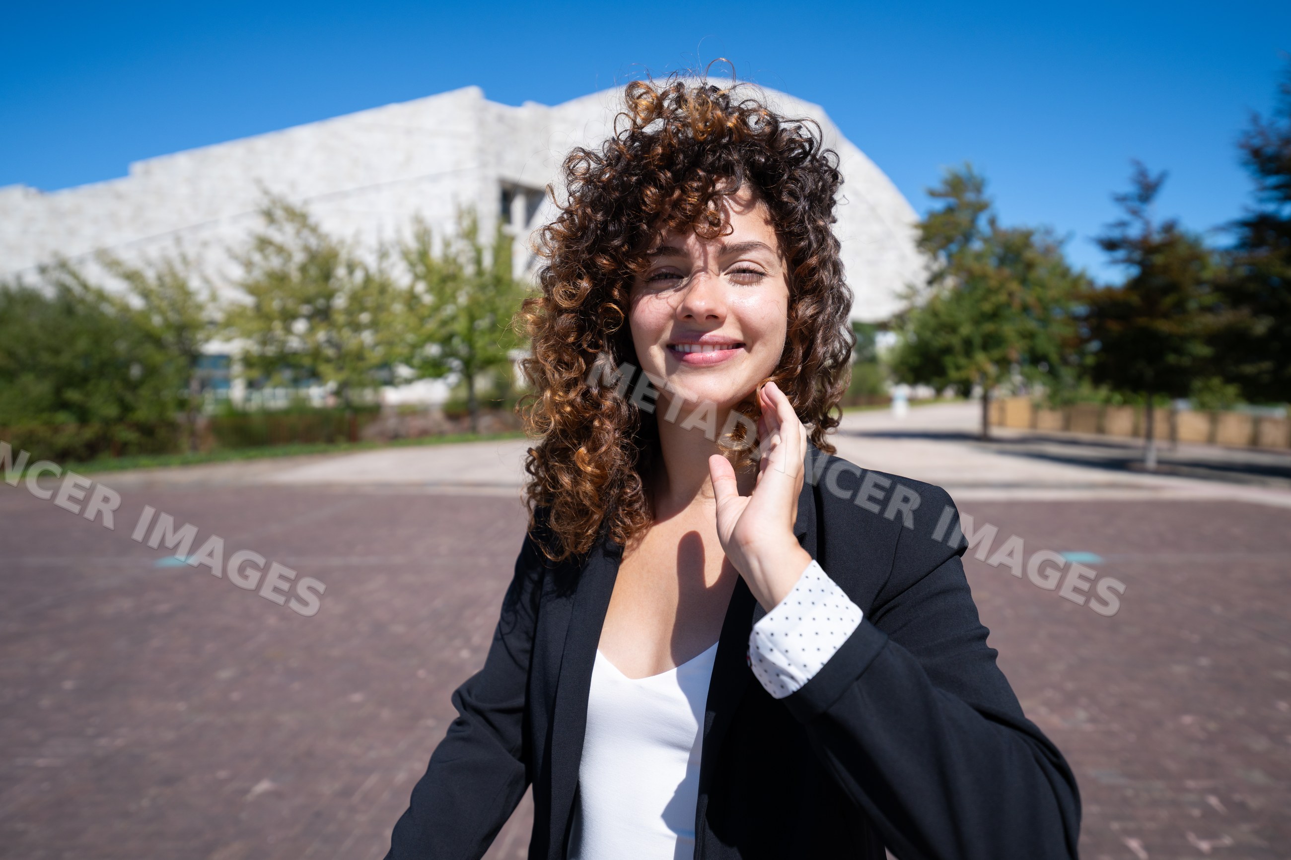 Businesswoman with curly hair smiling outdoors in Spain, santiago