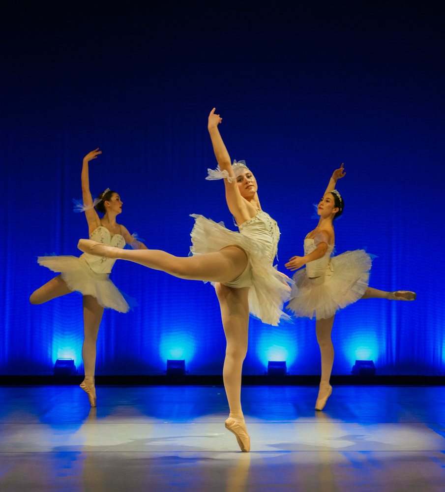 Three ballet dancers perform a classical dance on stage
