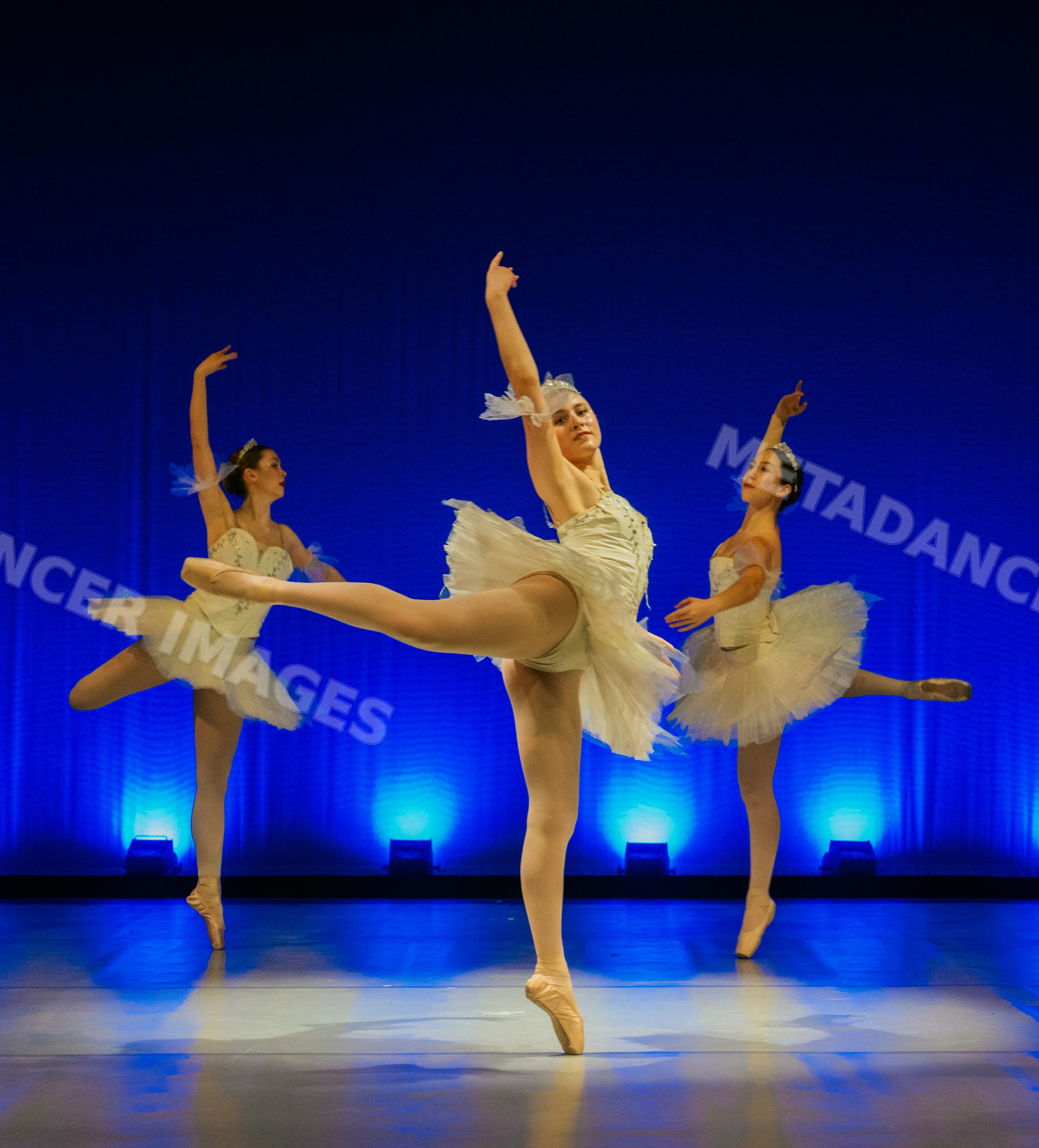 Three ballet dancers perform a classical dance on stage