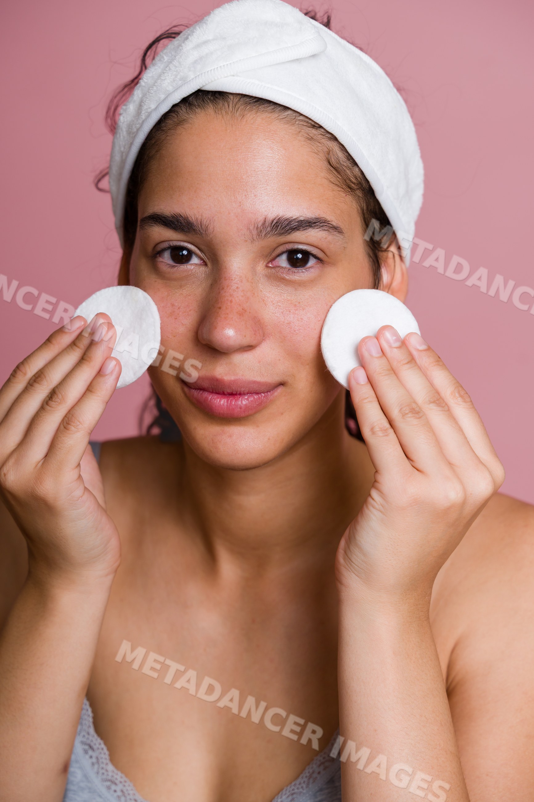 Hispanic woman cleansing face with cotton pads in beauty routine