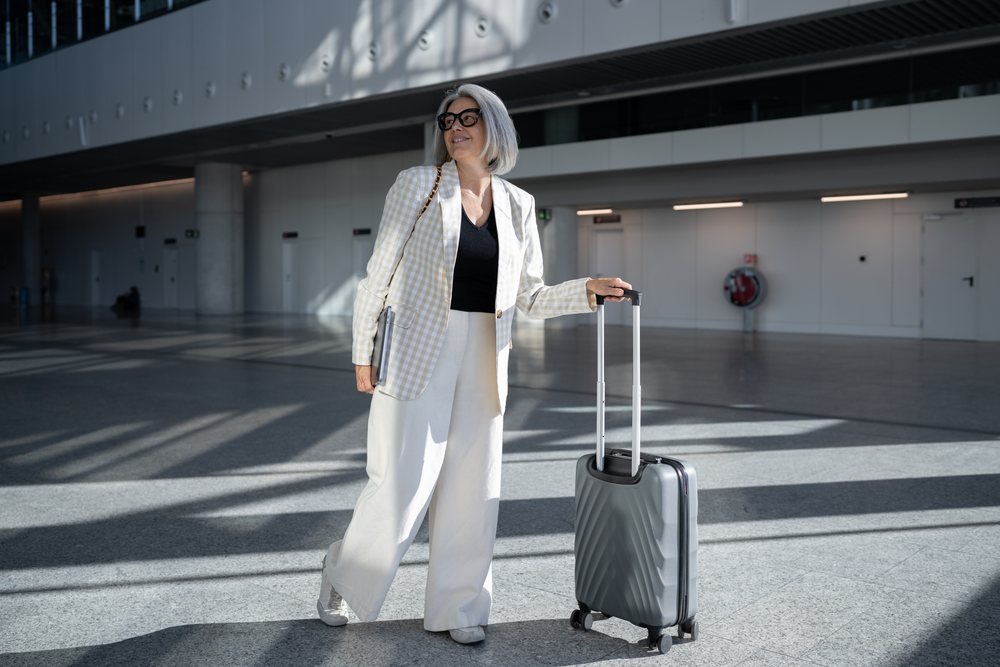 White woman walking with suitcase in airport terminal in Madrid Spain