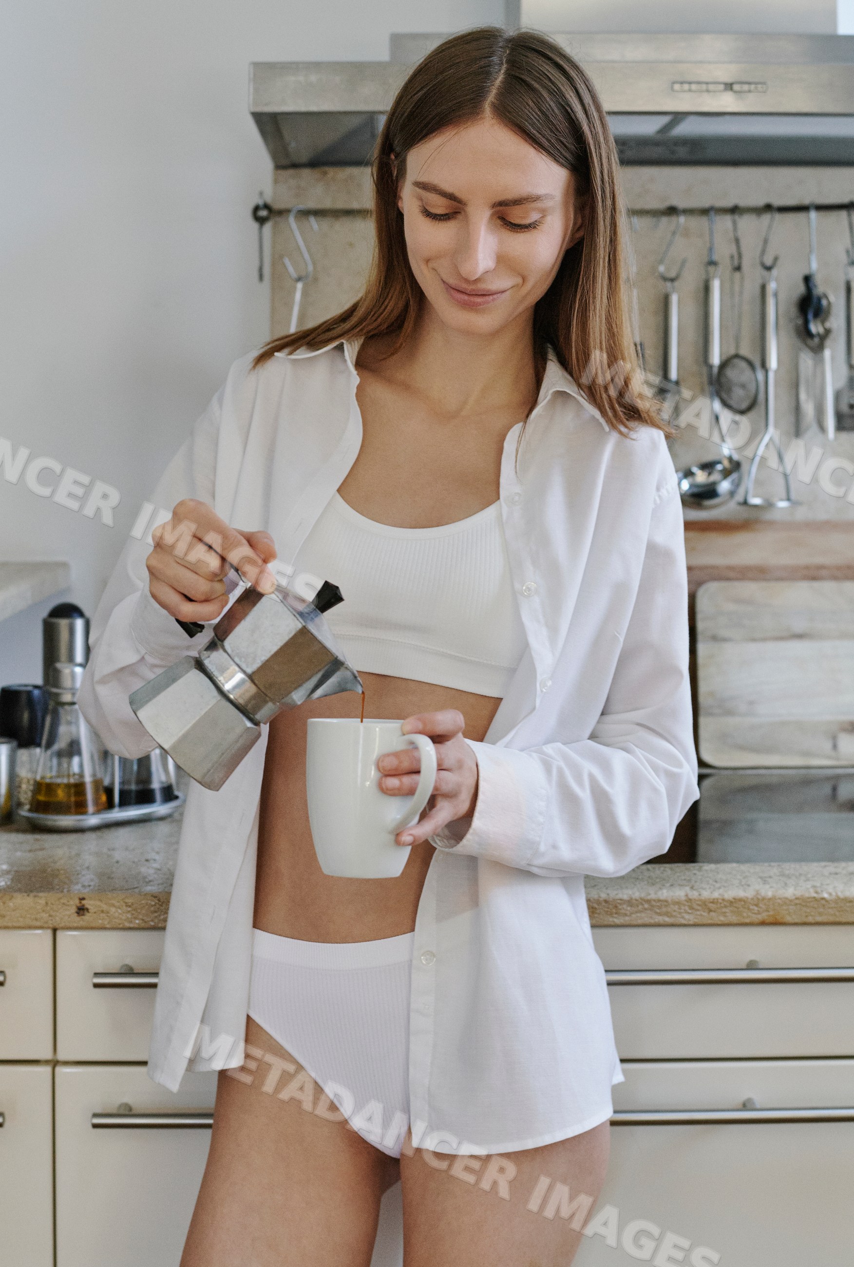 A white woman pours coffee from a stovetop coffee maker into a cup