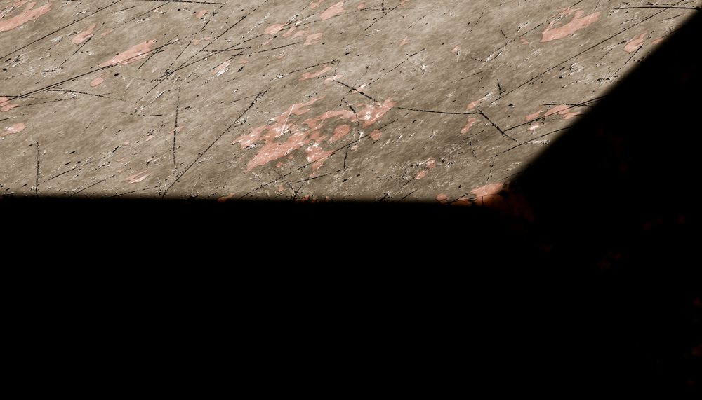 Worn concrete floor with paint spots and shadow