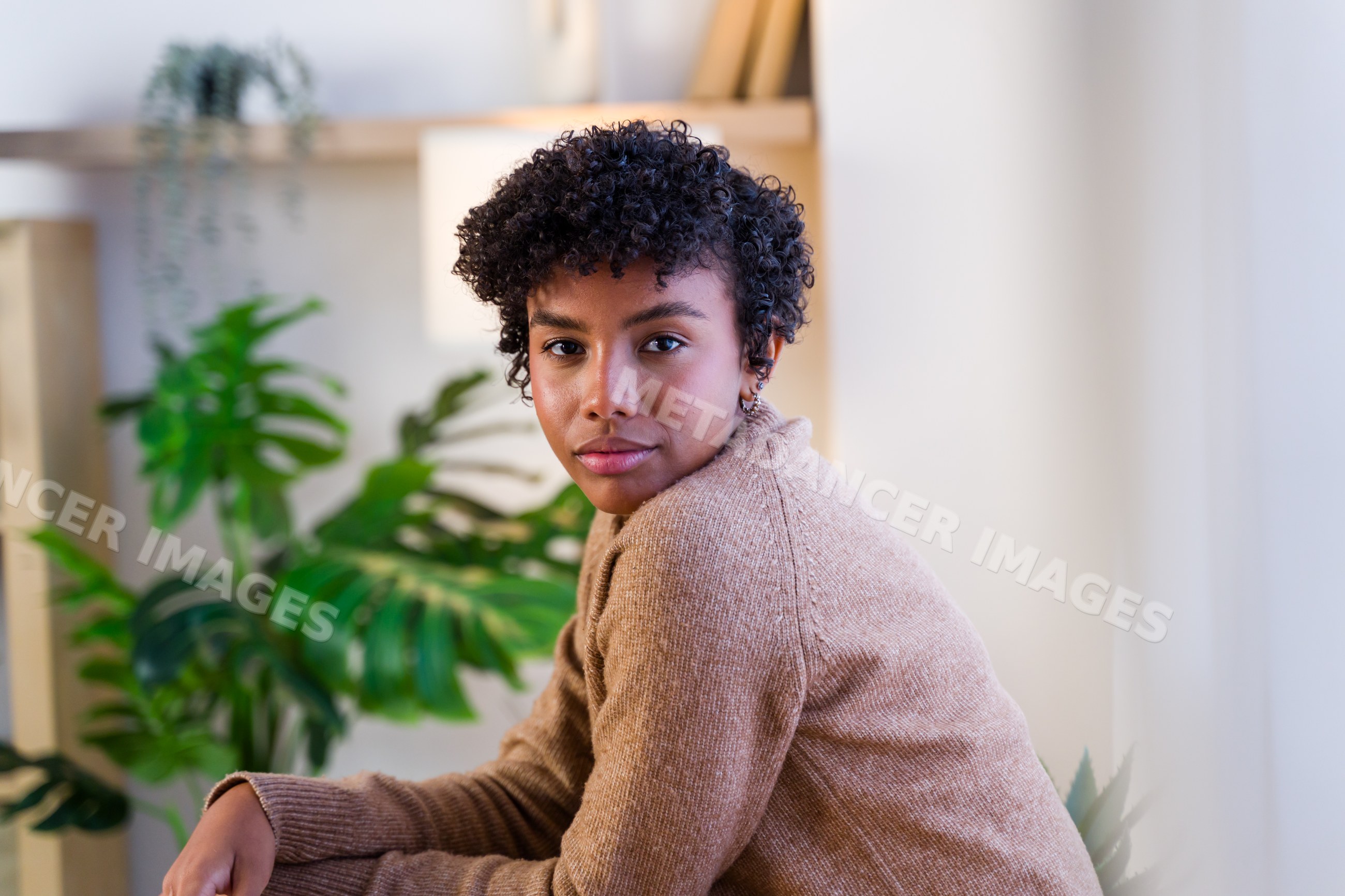 Young African American woman with curly hair wearing brown sweater