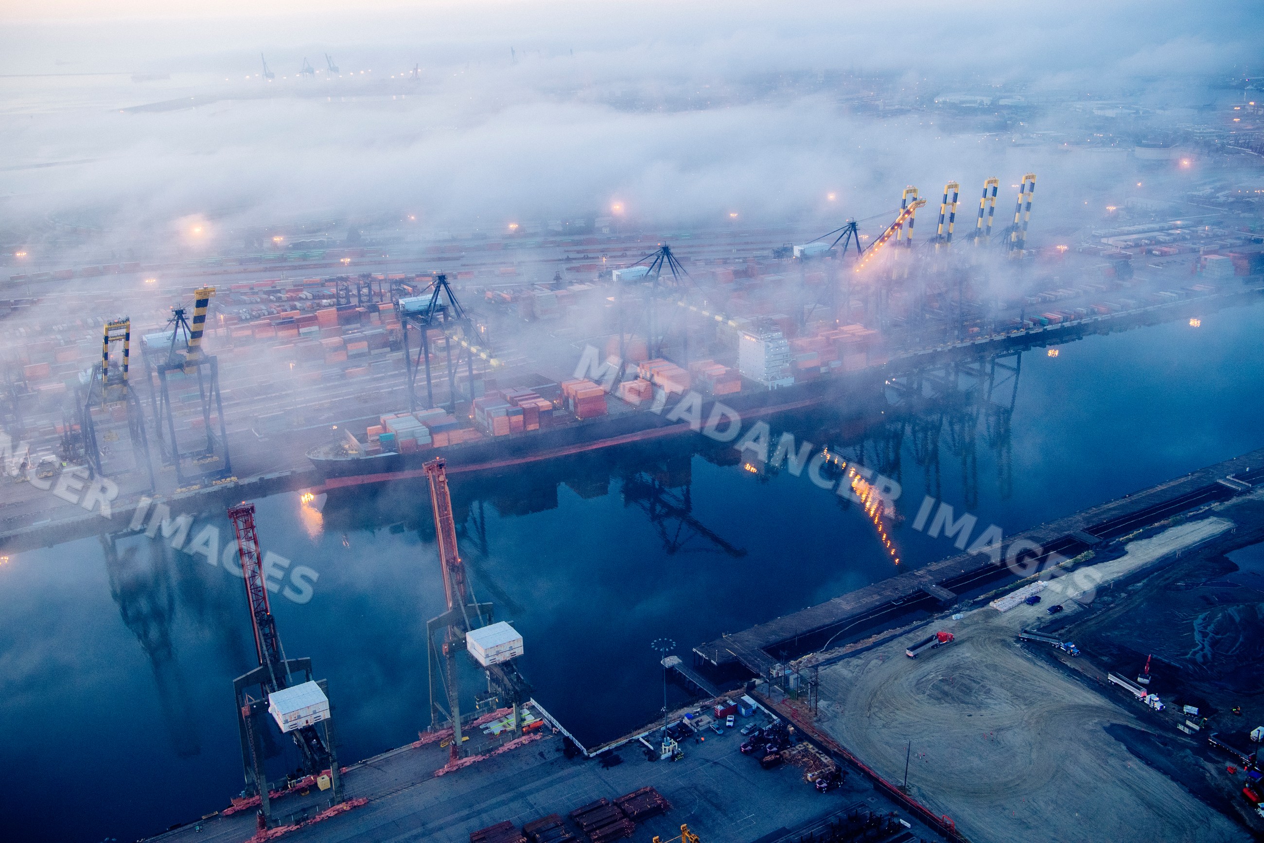 Container ship with cranes and containers at Port of Long Beach in fog