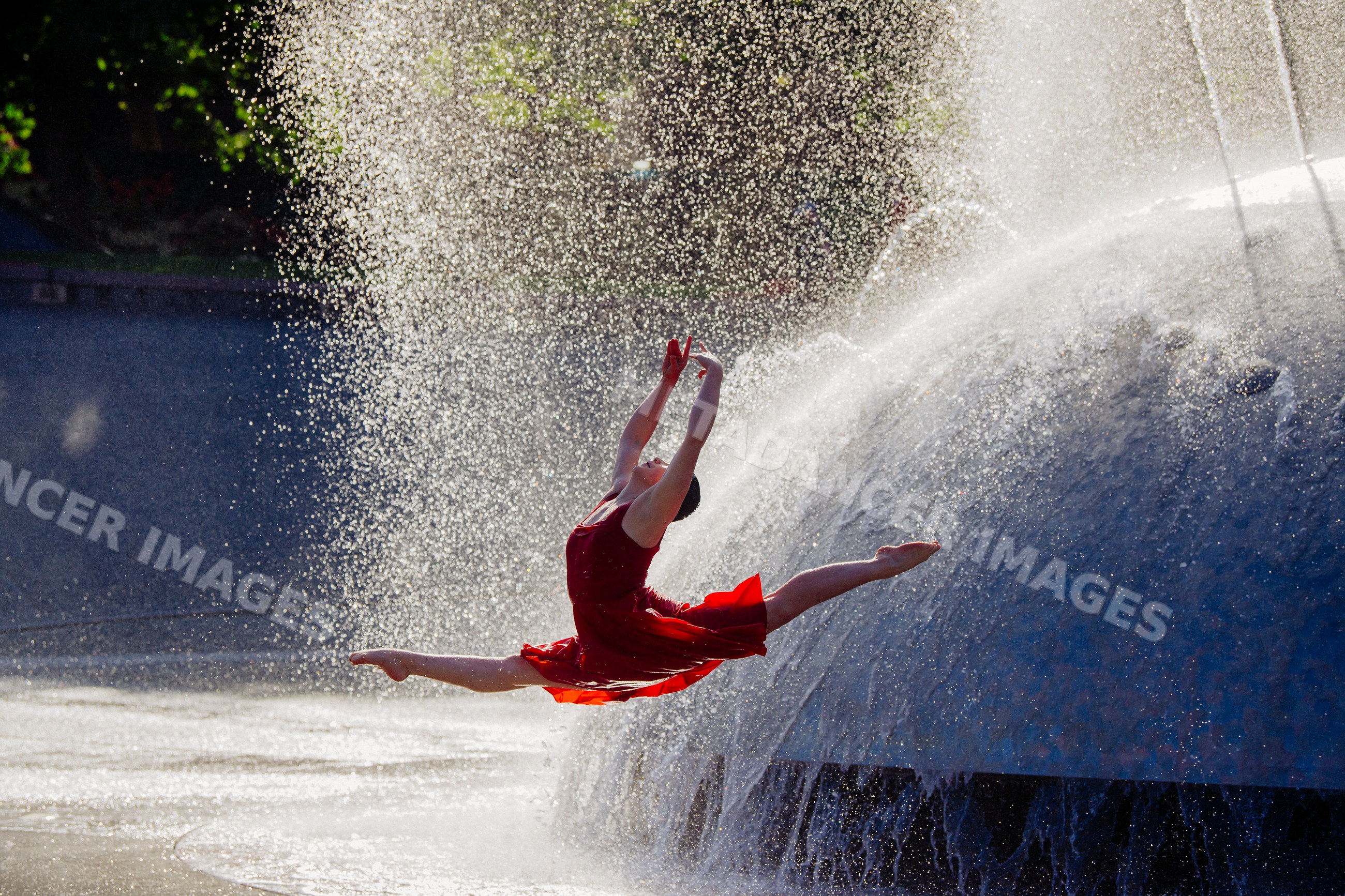 White dancer leaping with water fountain spray outdoors