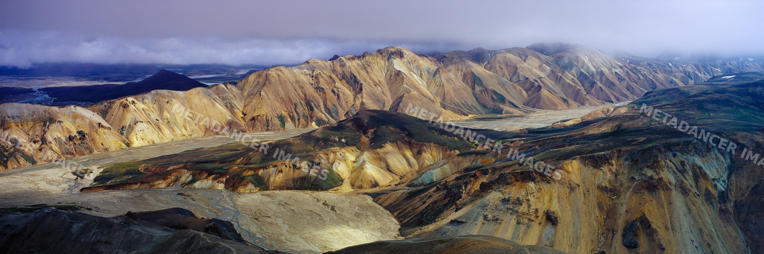 Aerial panoramic view of a mountain range with river valley and clouds