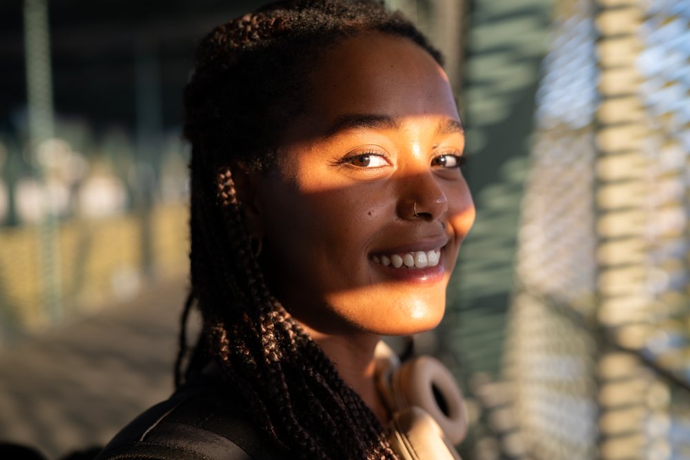 Young African American woman smiles warmly in natural sunlight