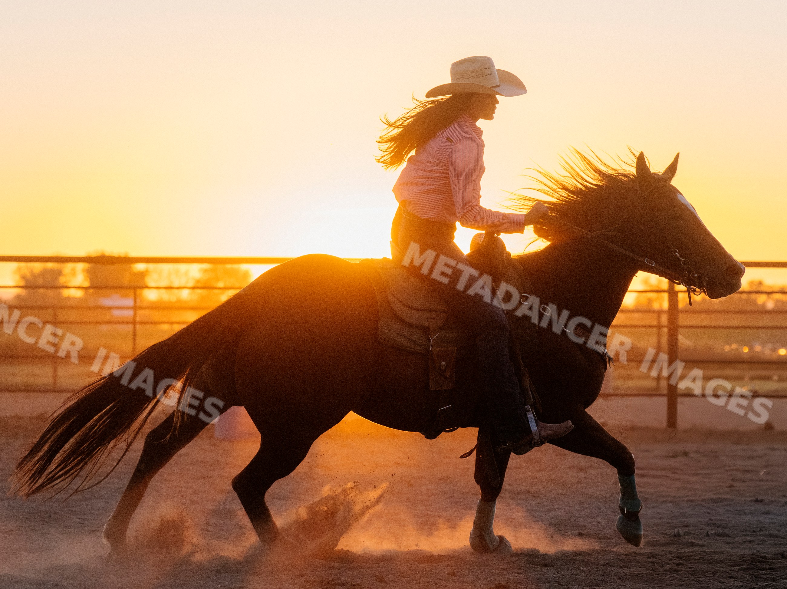 White woman horseback riding horse at sunset in outdoor arena
