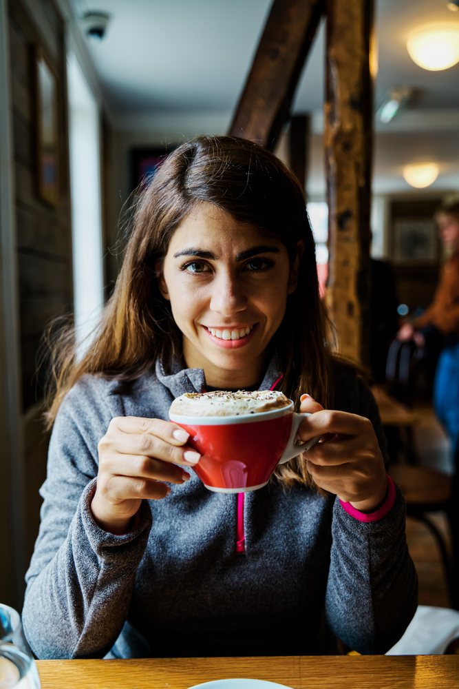 A white woman enjoys a cup of coffee in a cozy Iceland cafe
