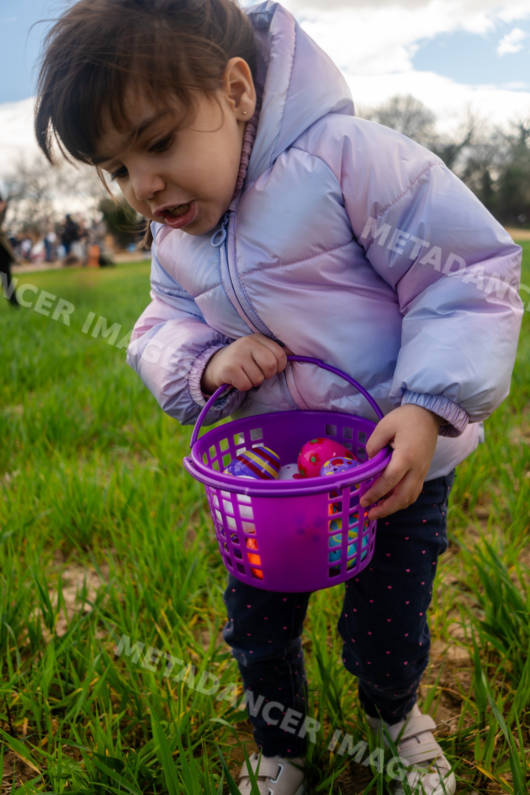 Young white girl holding a basket full of colorful eggs outdoors