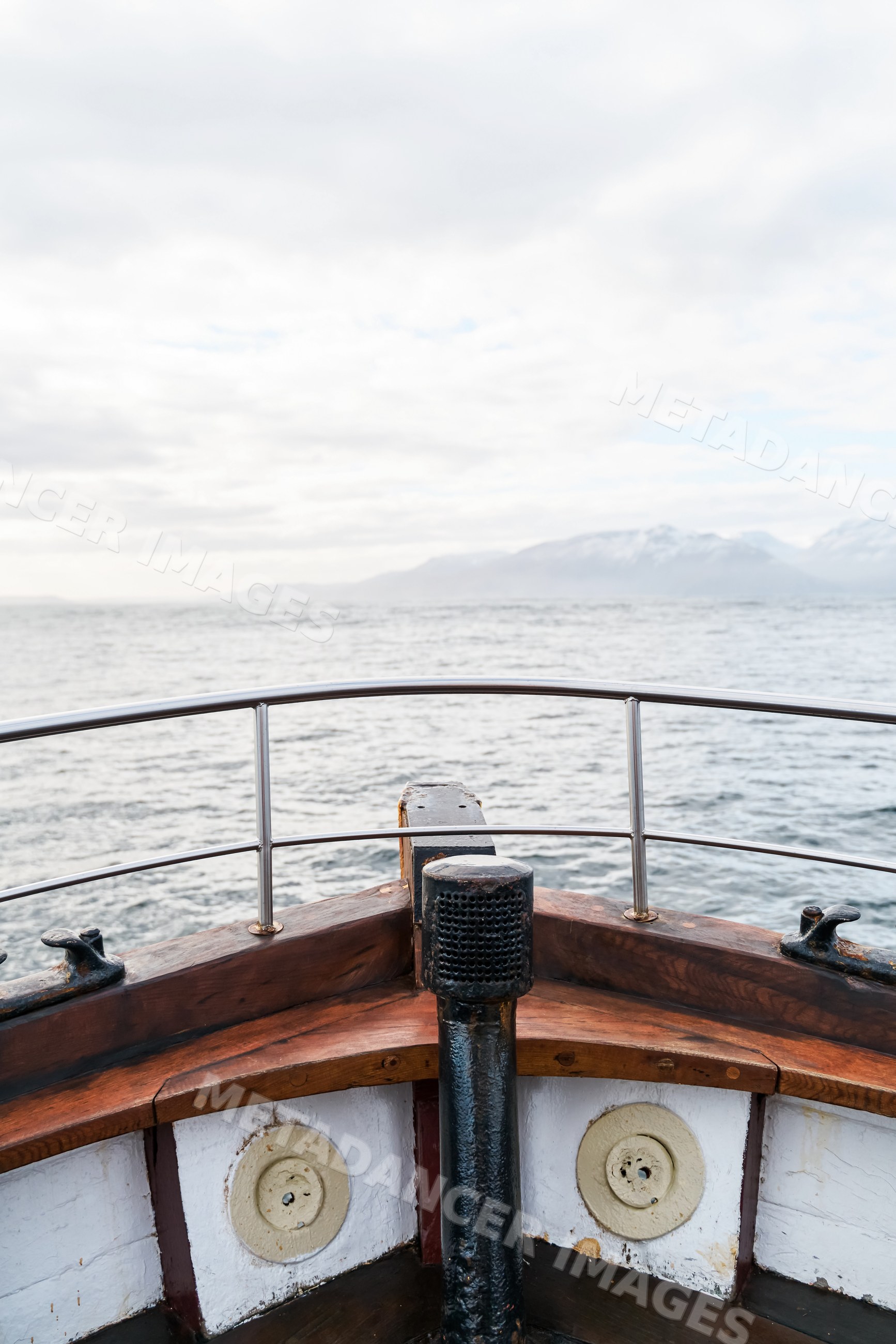 View from the bow of a wooden boat overlooking the ocean and mountains