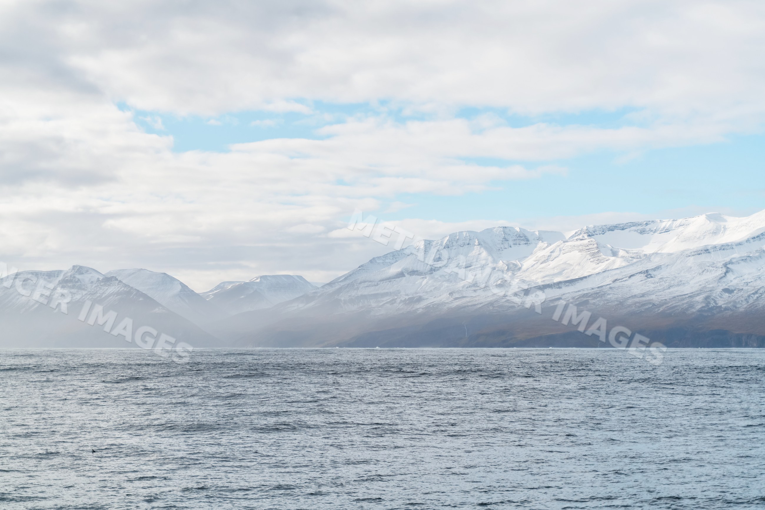 Snowy mountains overlooking the misty ocean coast