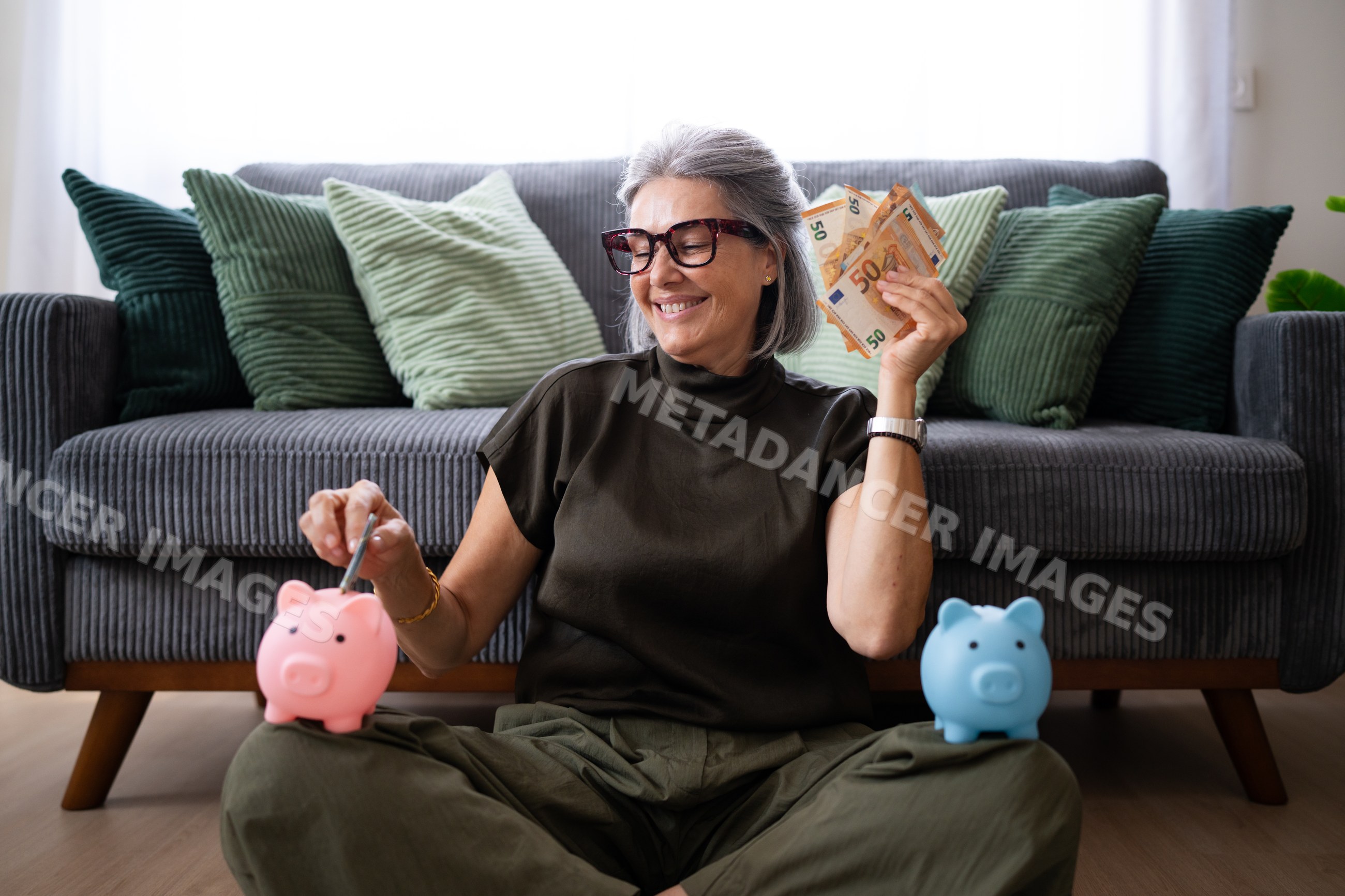 White woman saving money with piggy banks in living room in Spain