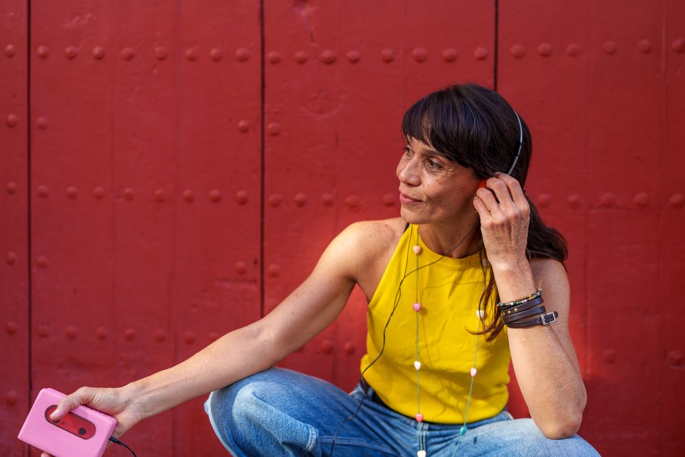 Hispanic woman listening to music with headphones and cassette player