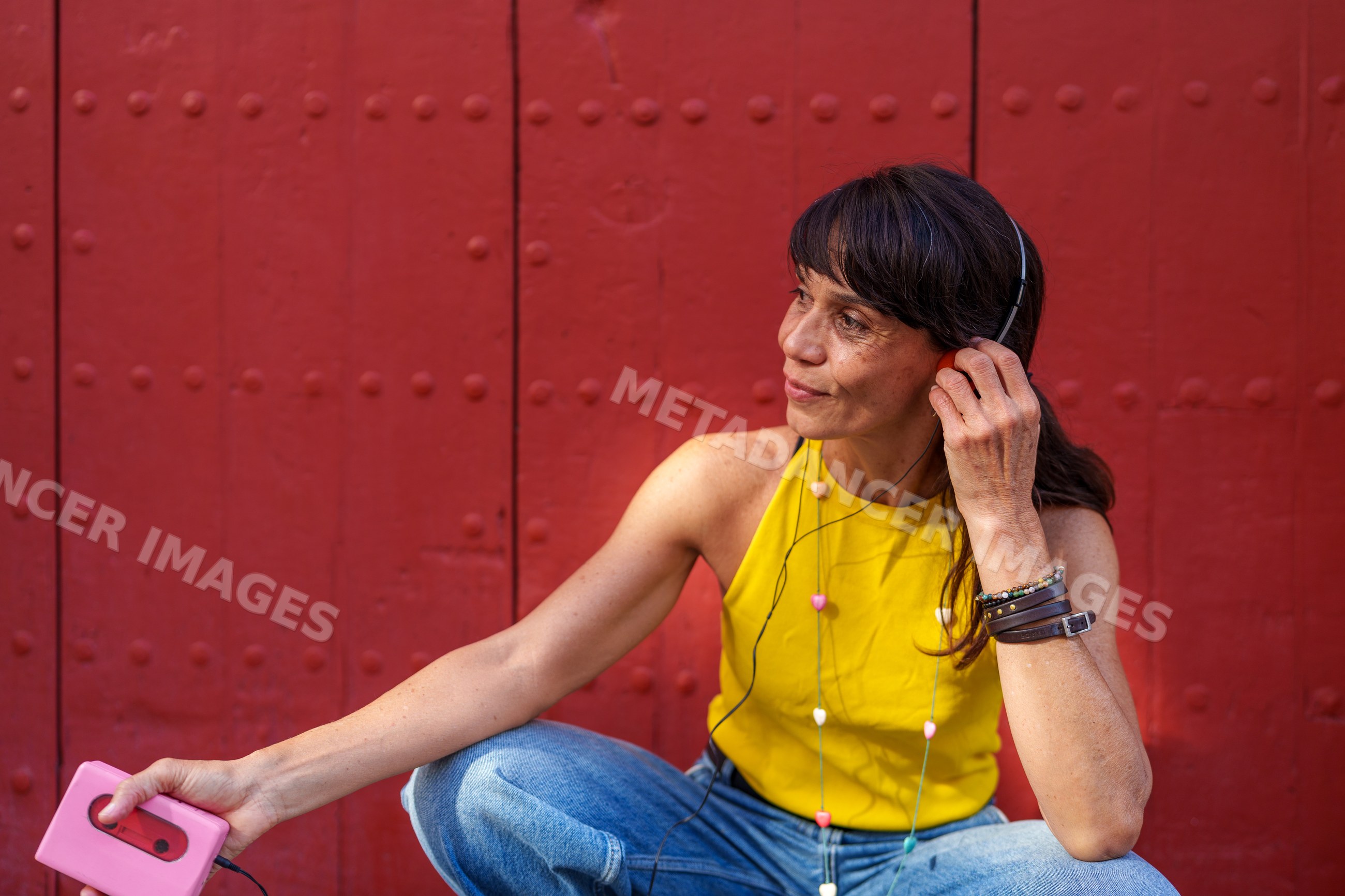 Hispanic woman listening to music with headphones and cassette player