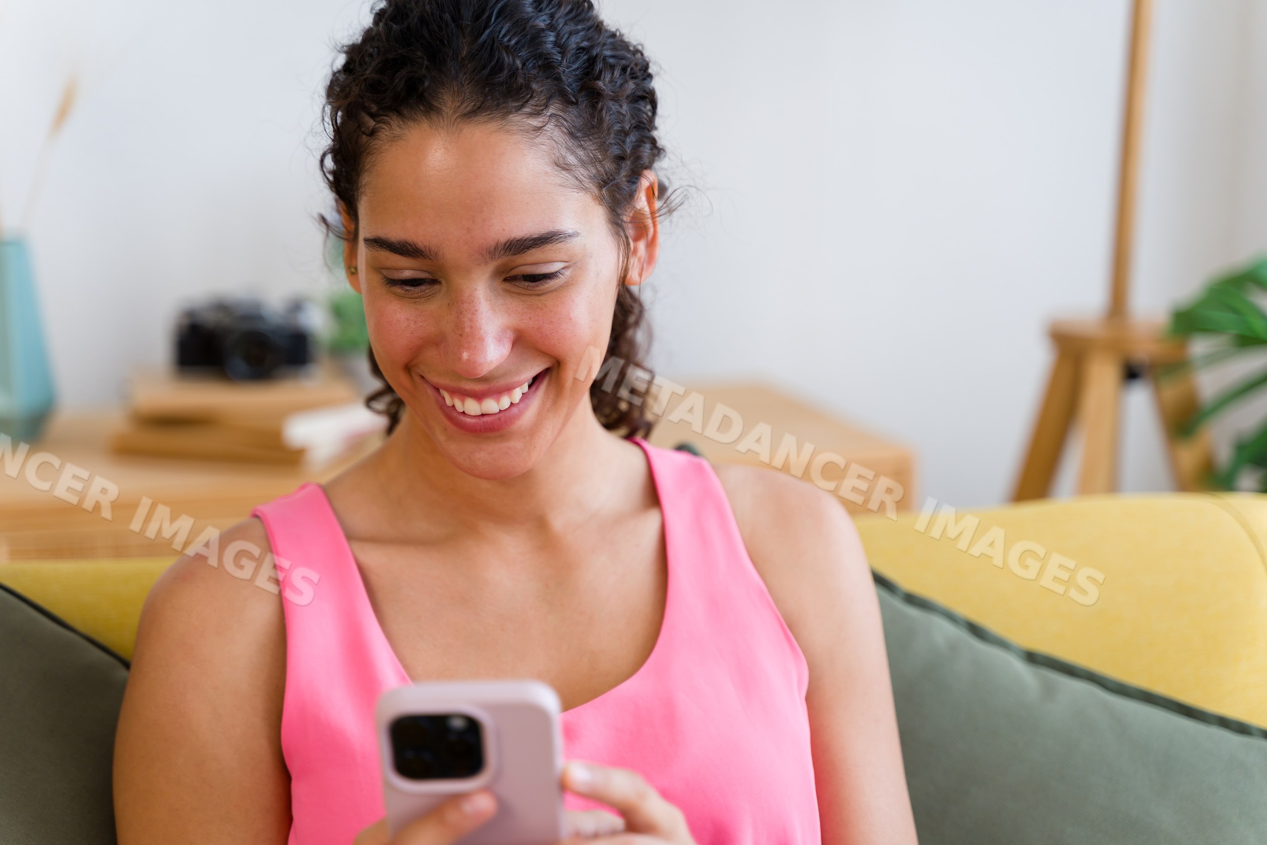 A Hispanic woman happily uses her smartphone