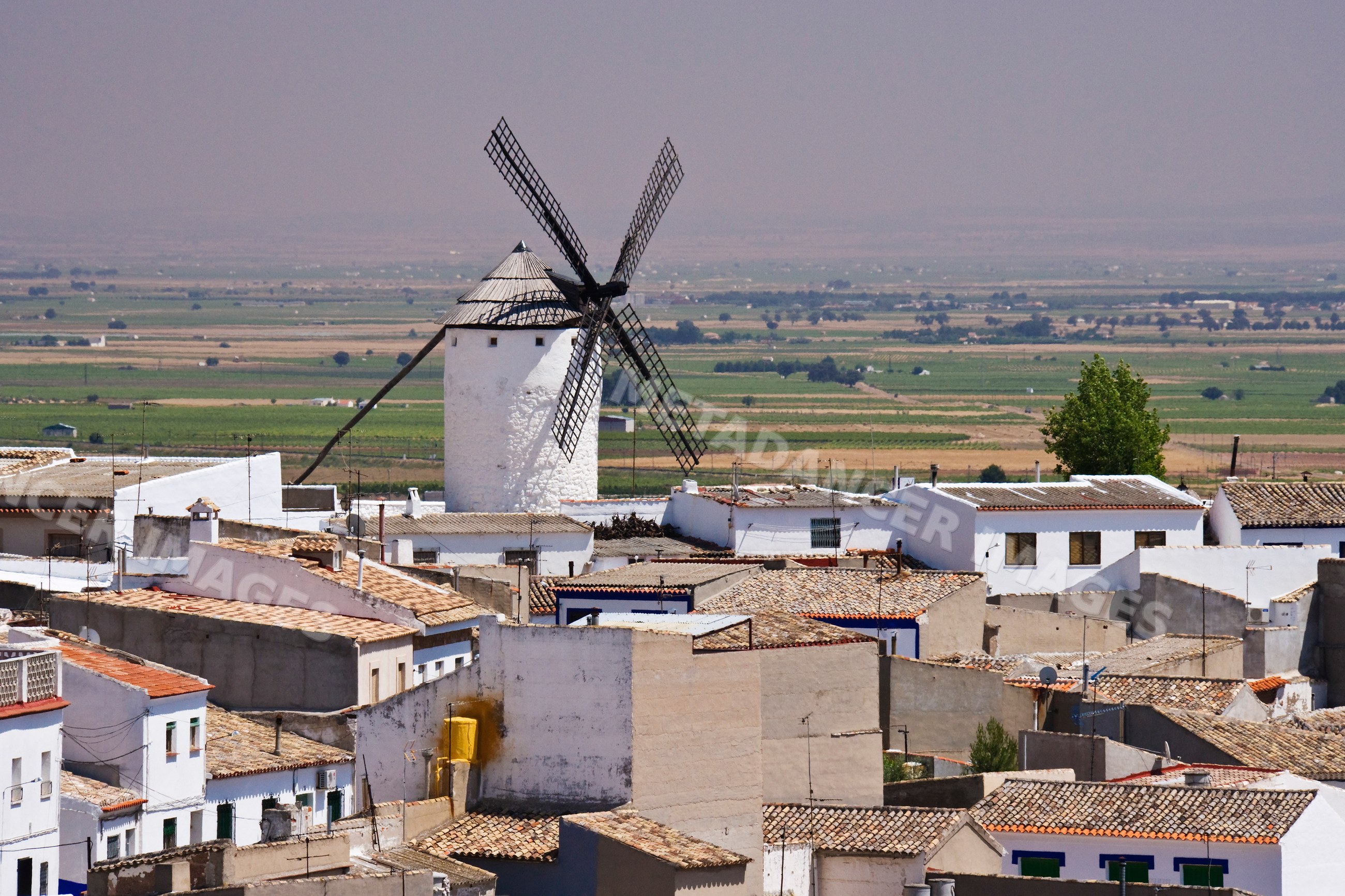 Windmill above rooftops in rural la mancha village
