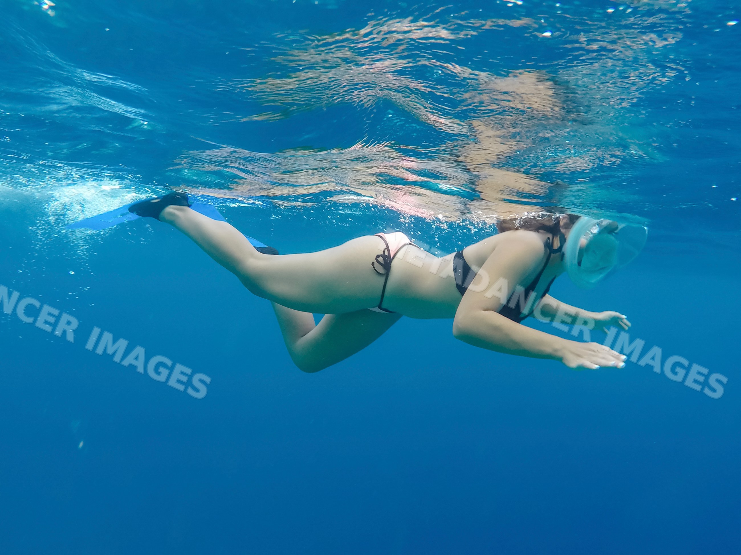 A woman snorkeling underwater in the clear blue ocean of the Maldives