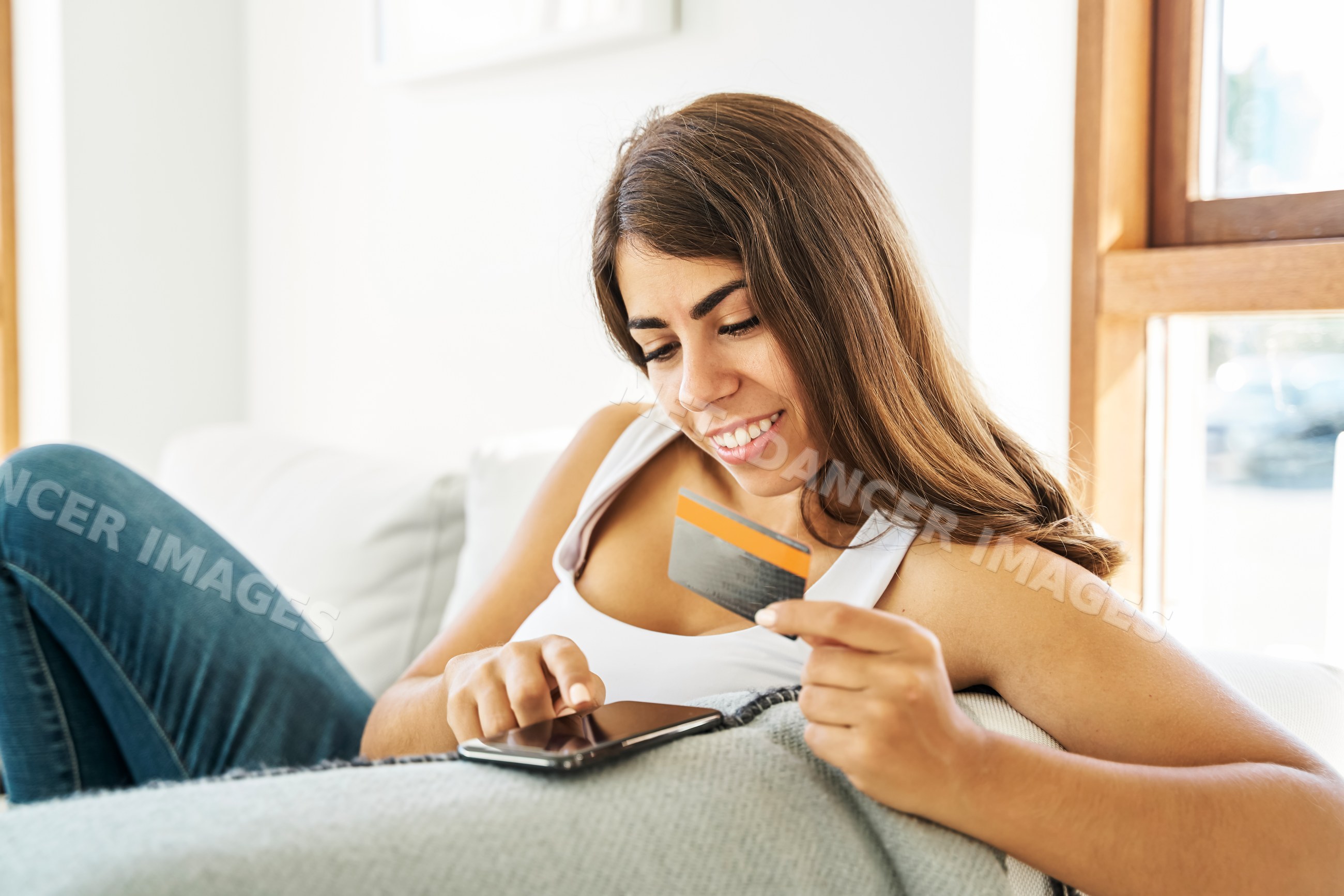A white woman shops online with a credit card and smartphone