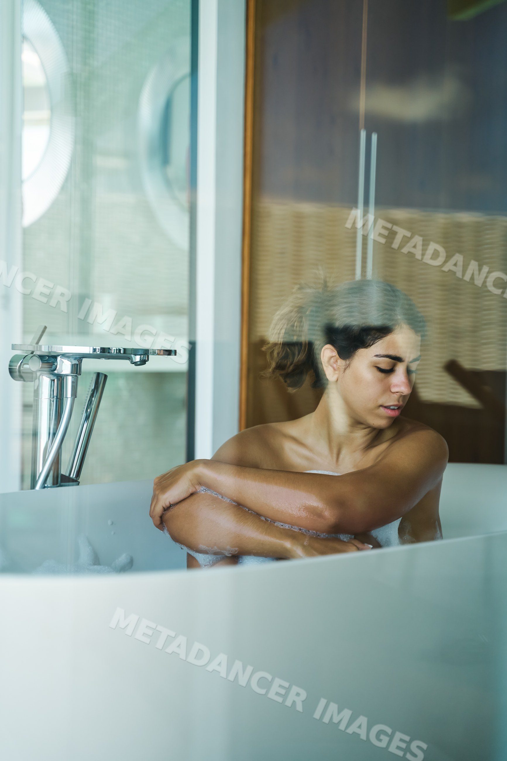 A white woman relaxes in a foam-filled bathtub in a Maldives bathroom