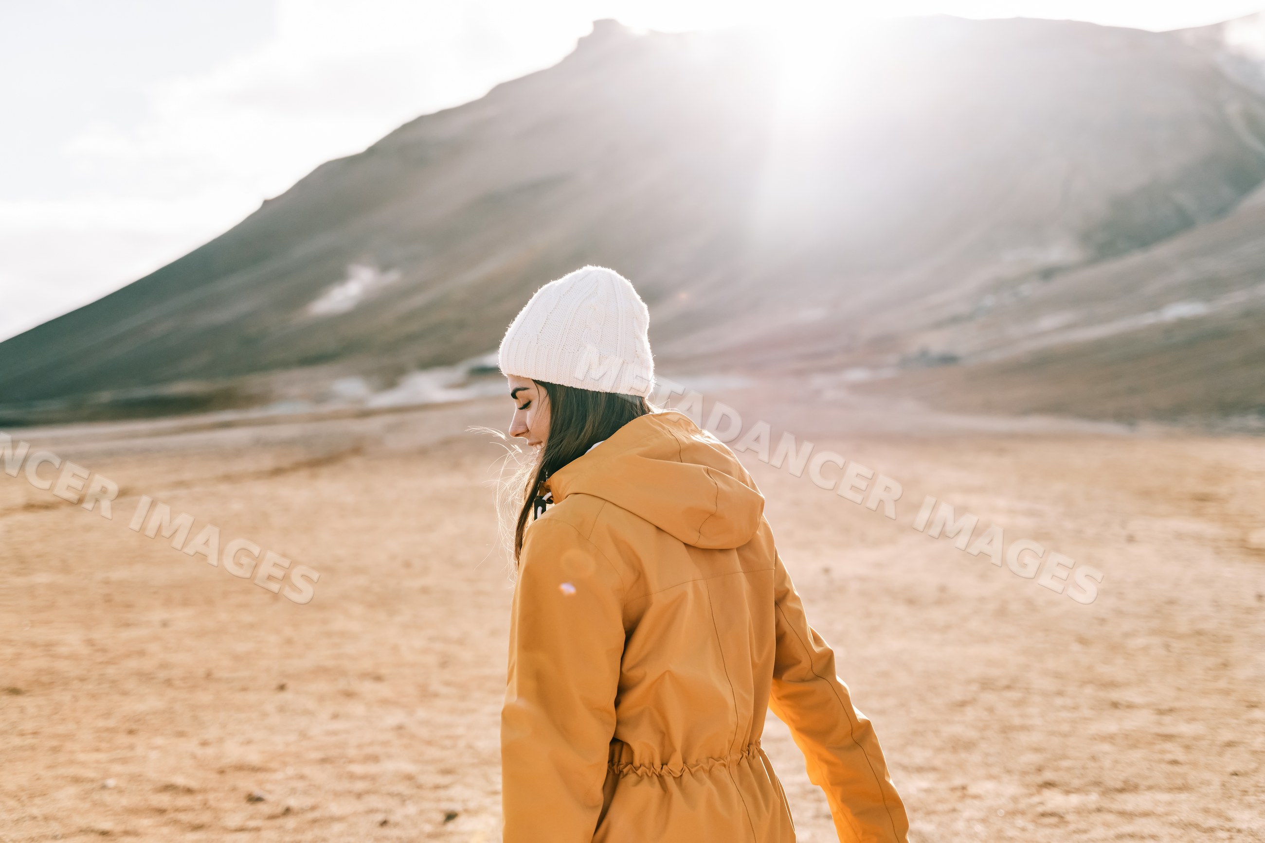 A white woman walks outdoors by a mountain