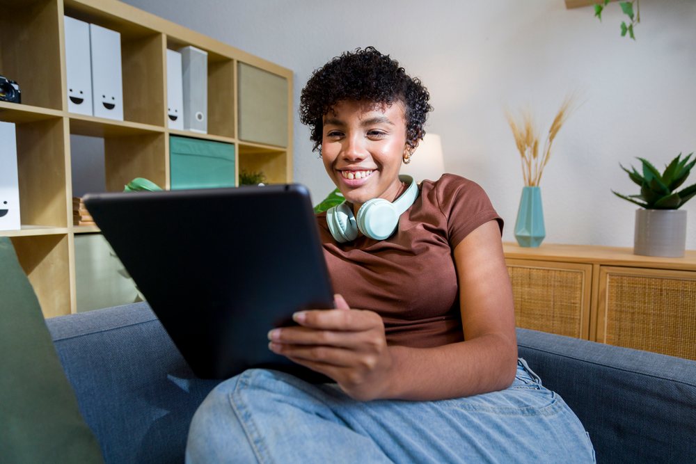 Young African American woman using tablet and relaxing on sofa at home