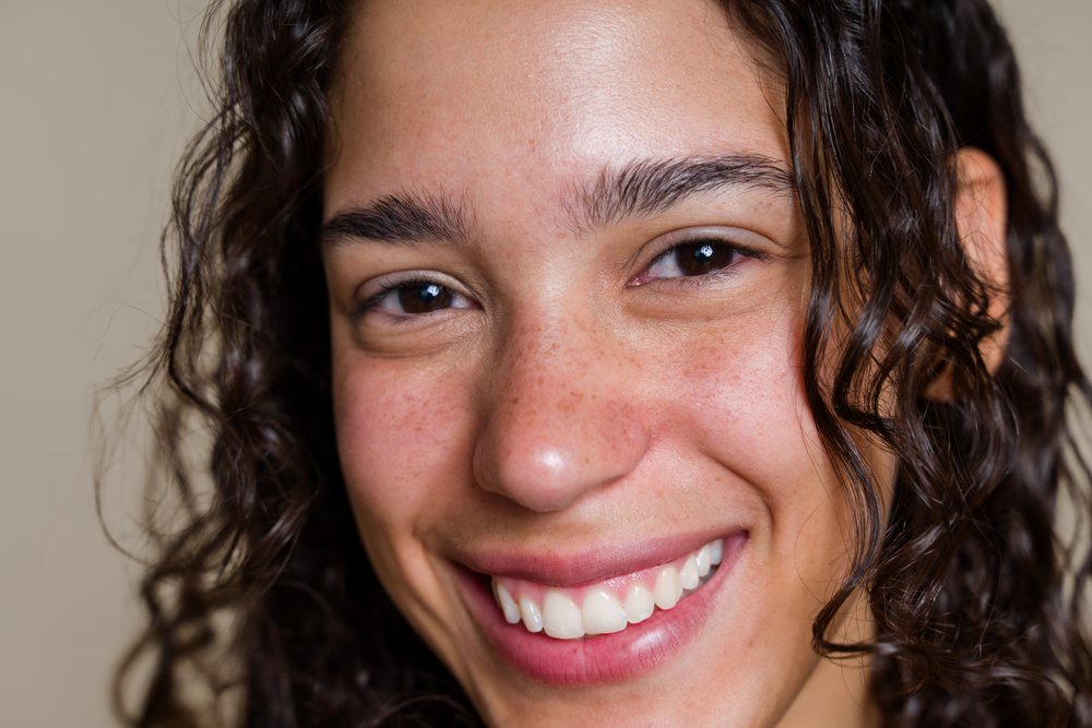 Smiling Hispanic woman with curly hair in close-up portrait