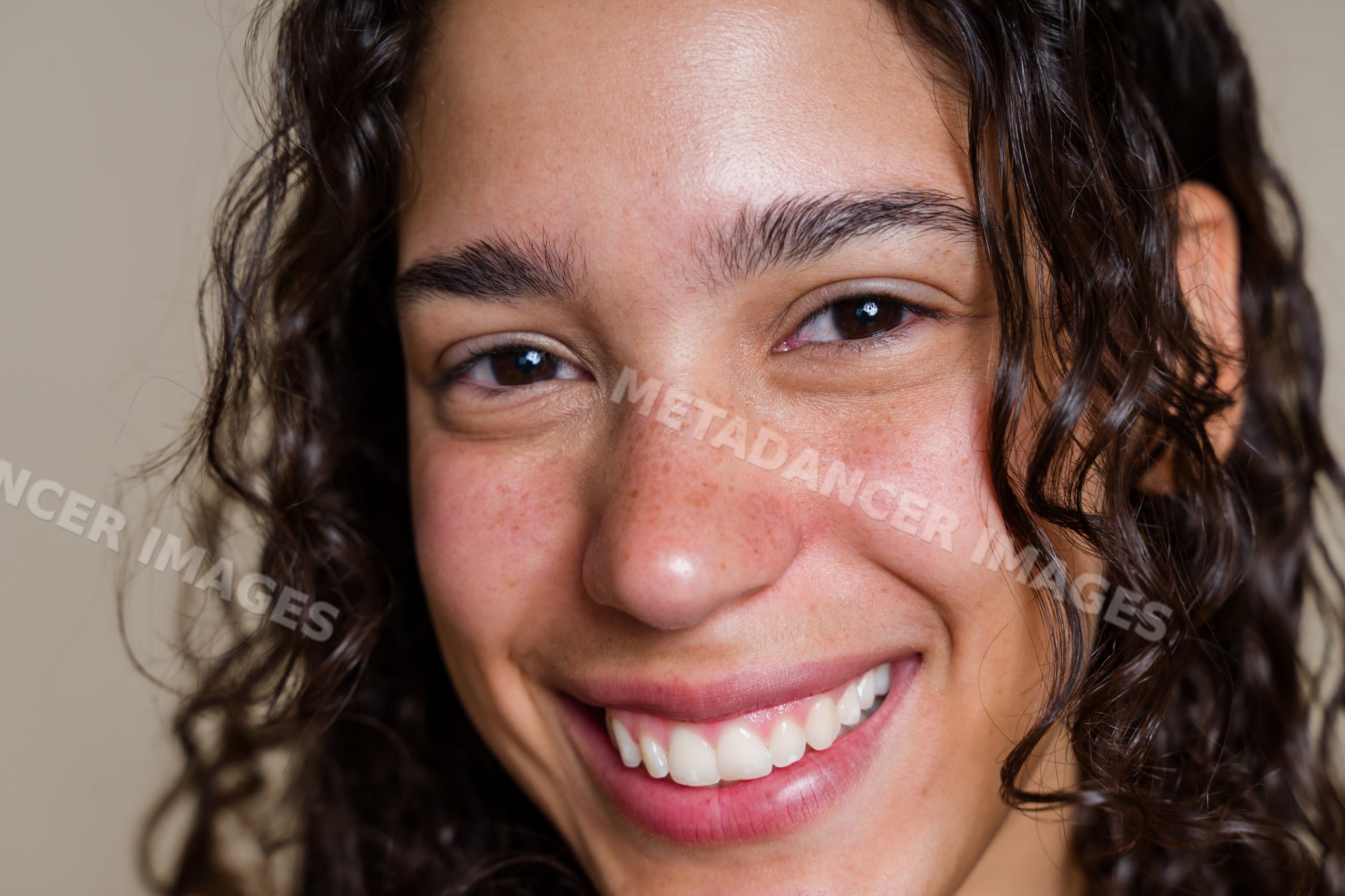 Smiling Hispanic woman with curly hair in close-up portrait