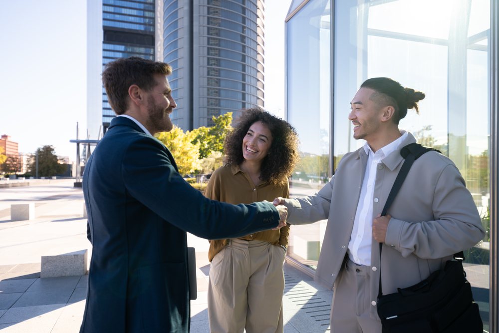 Business handshake between white professionals outside modern office