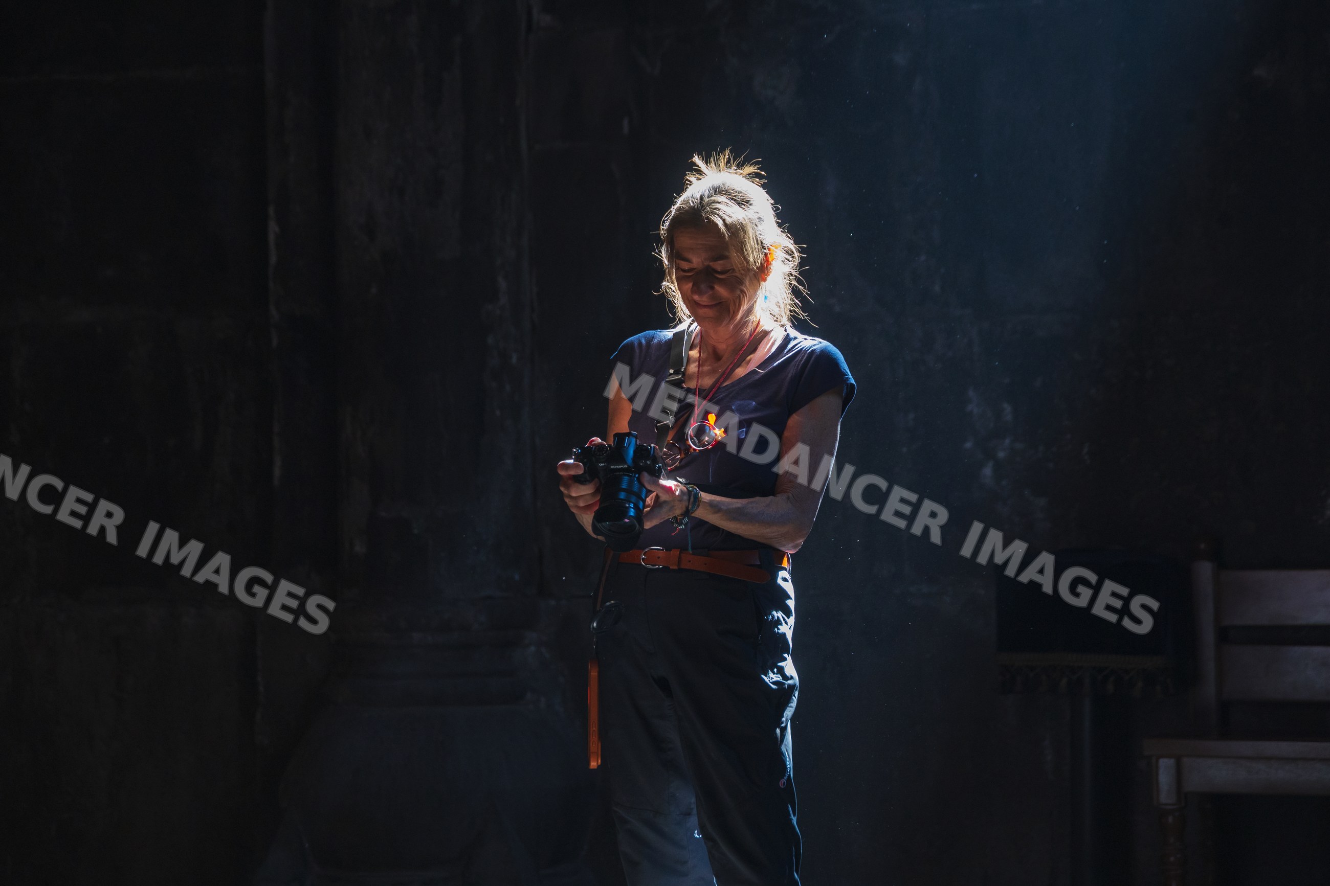 Woman photographer using camera inside geghart monastery in Armenia