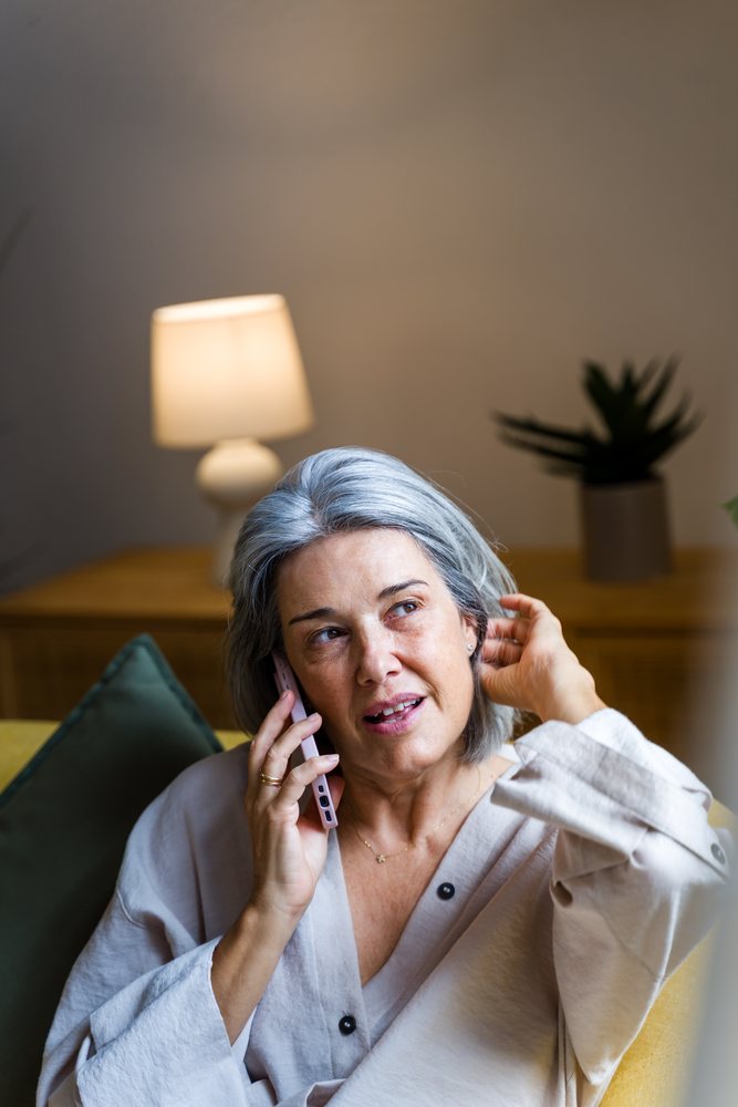 White woman talking on phone while sitting on couch
