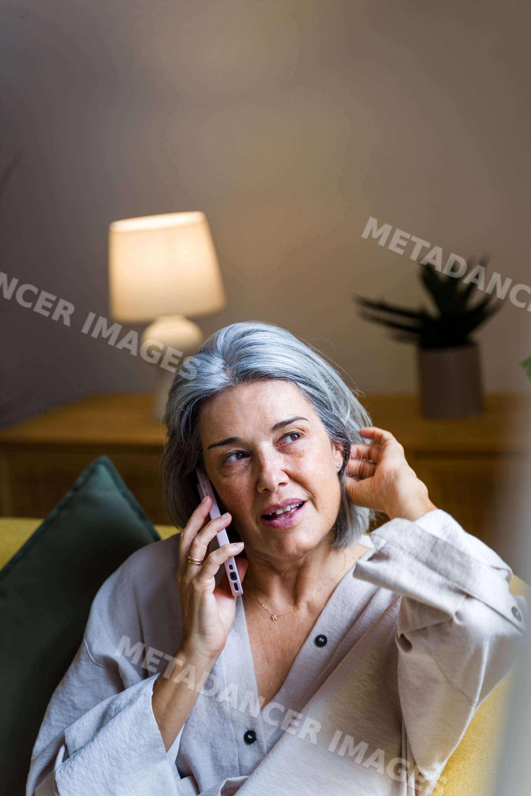 White woman talking on phone while sitting on couch