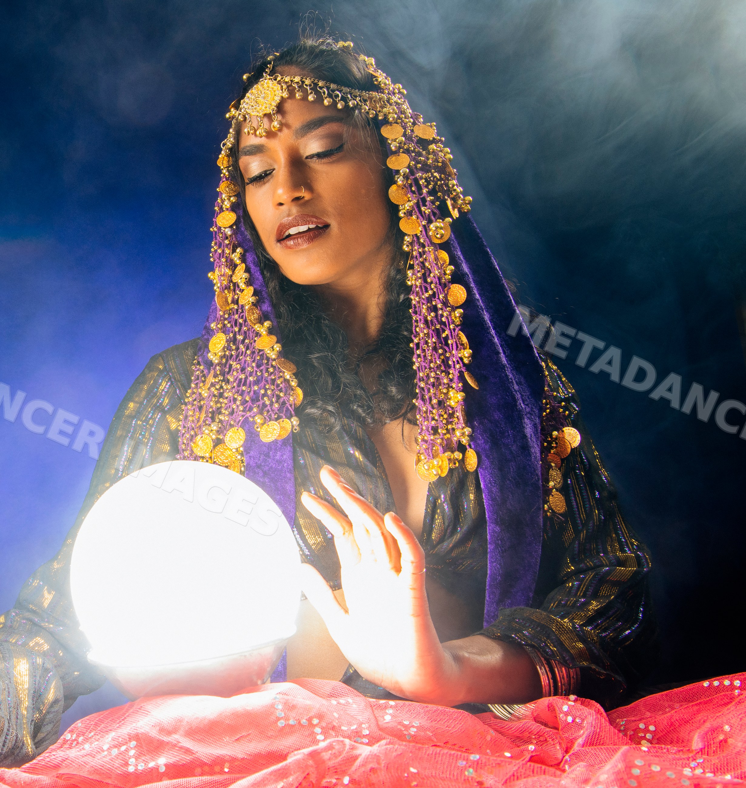 A South Asian woman fortune teller gazes into a glowing crystal ball