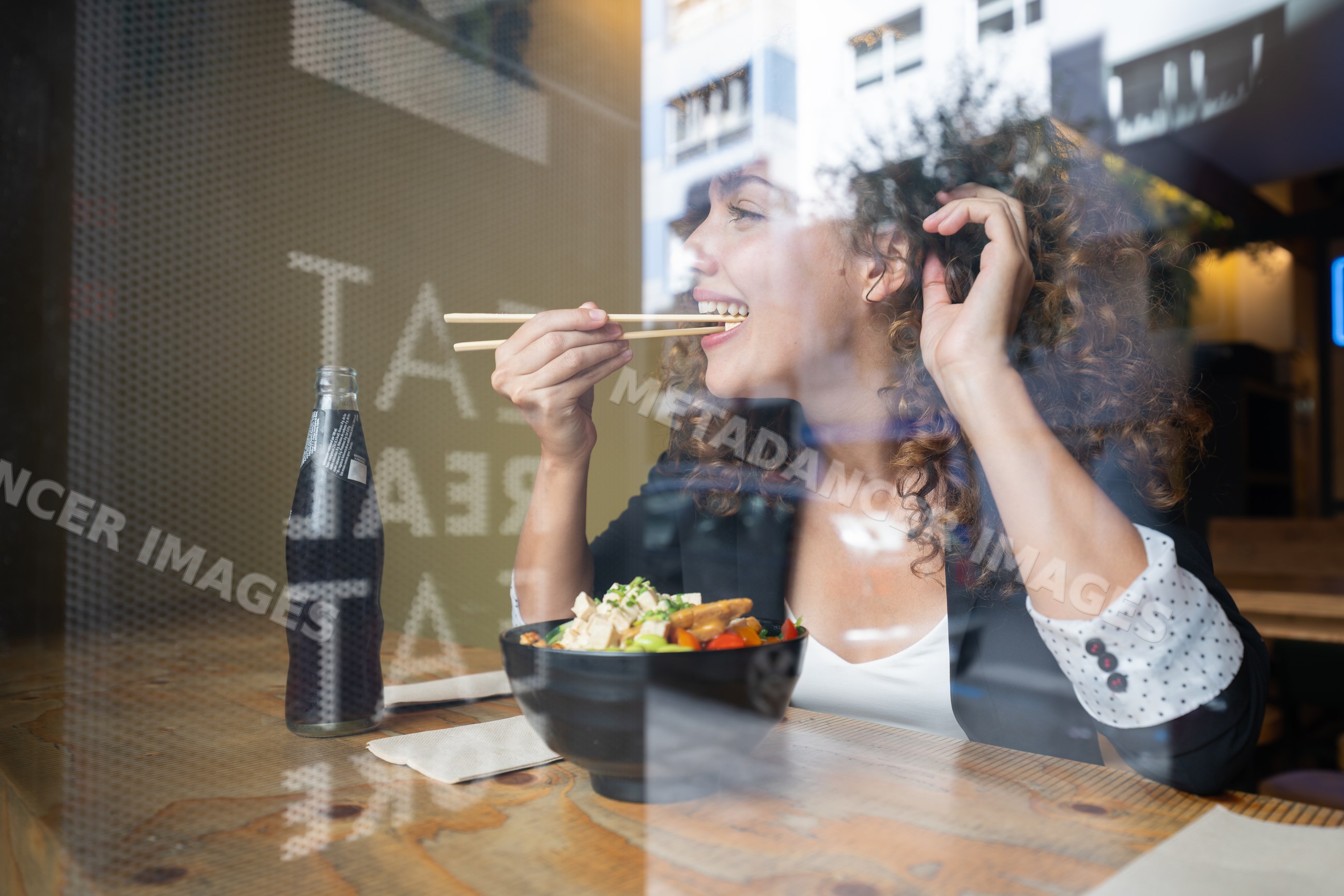 Businesswoman eating lunch with chopsticks inside restaurant in Spain