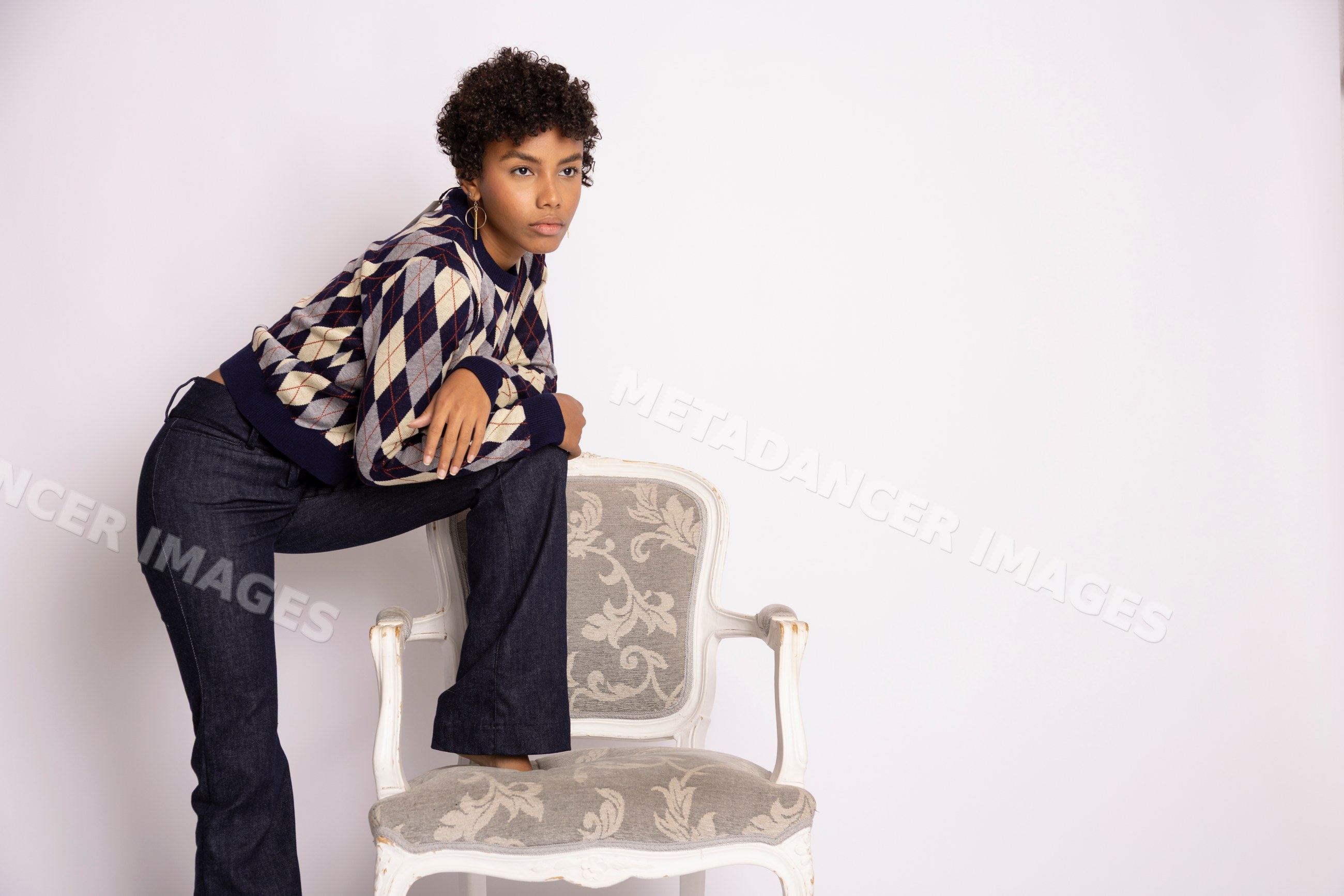 Young Hispanic woman posing with armchair in fashion studio
