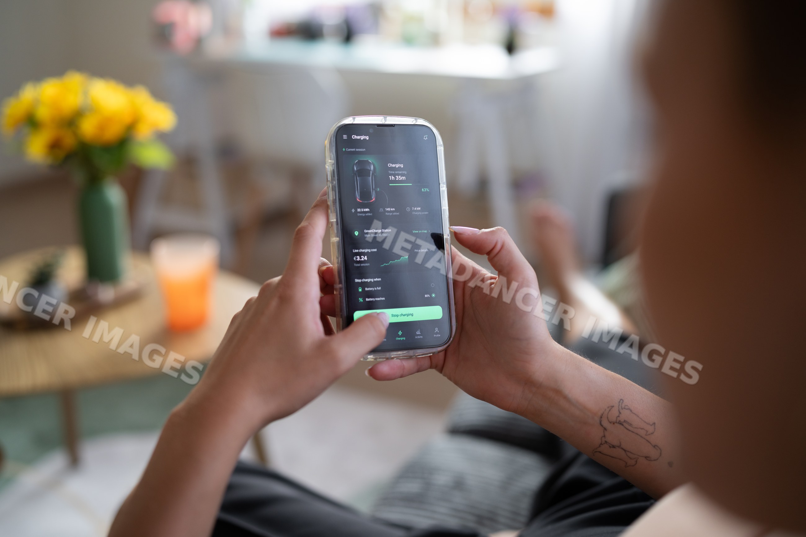 A white person monitors electric vehicle charging using a smartphone