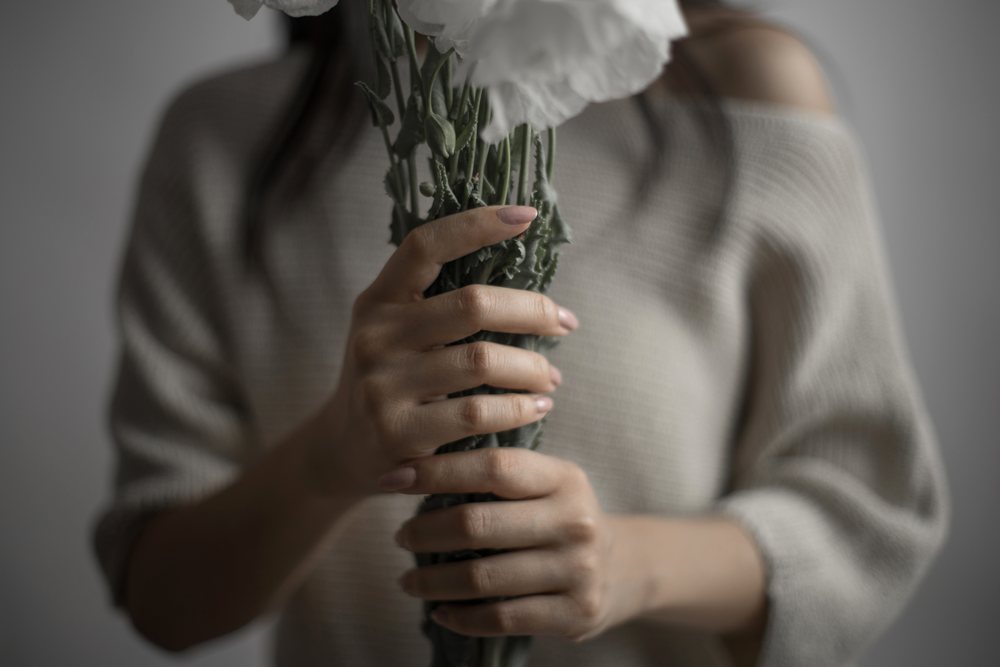 Southeast Asian woman holding white carnations bouquet