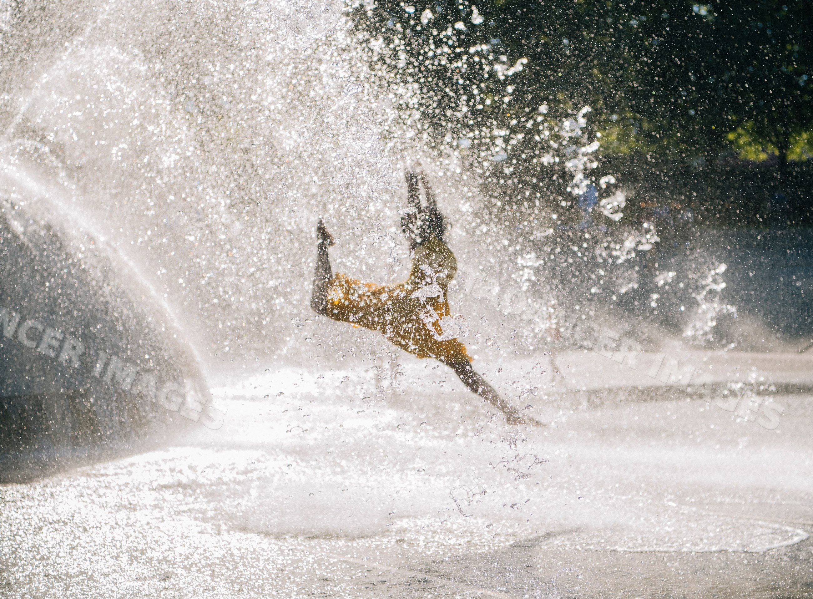 South Asian child playing and splashing water at outdoor fountain