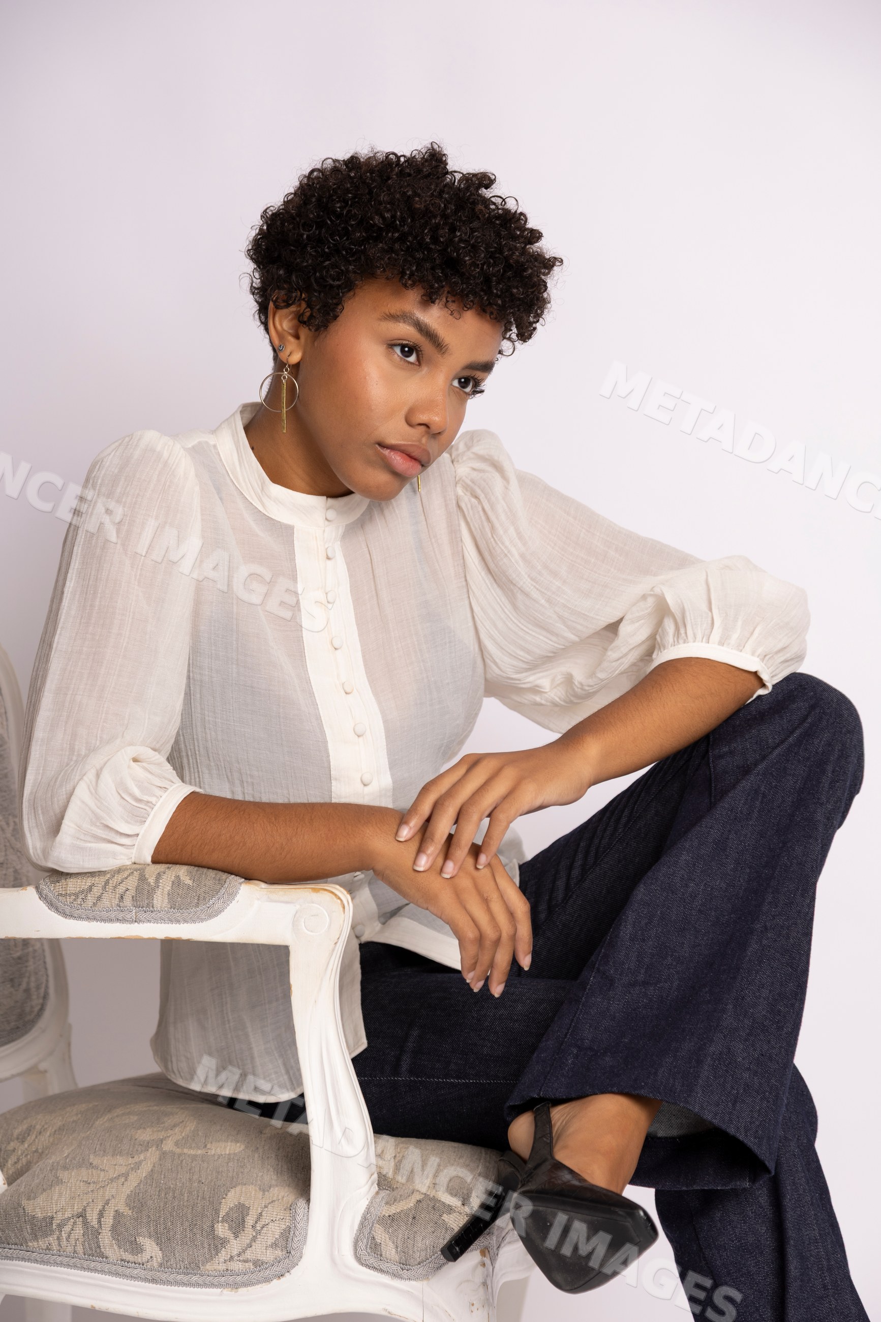 Hispanic woman sitting thoughtfully on chair wearing white blouse