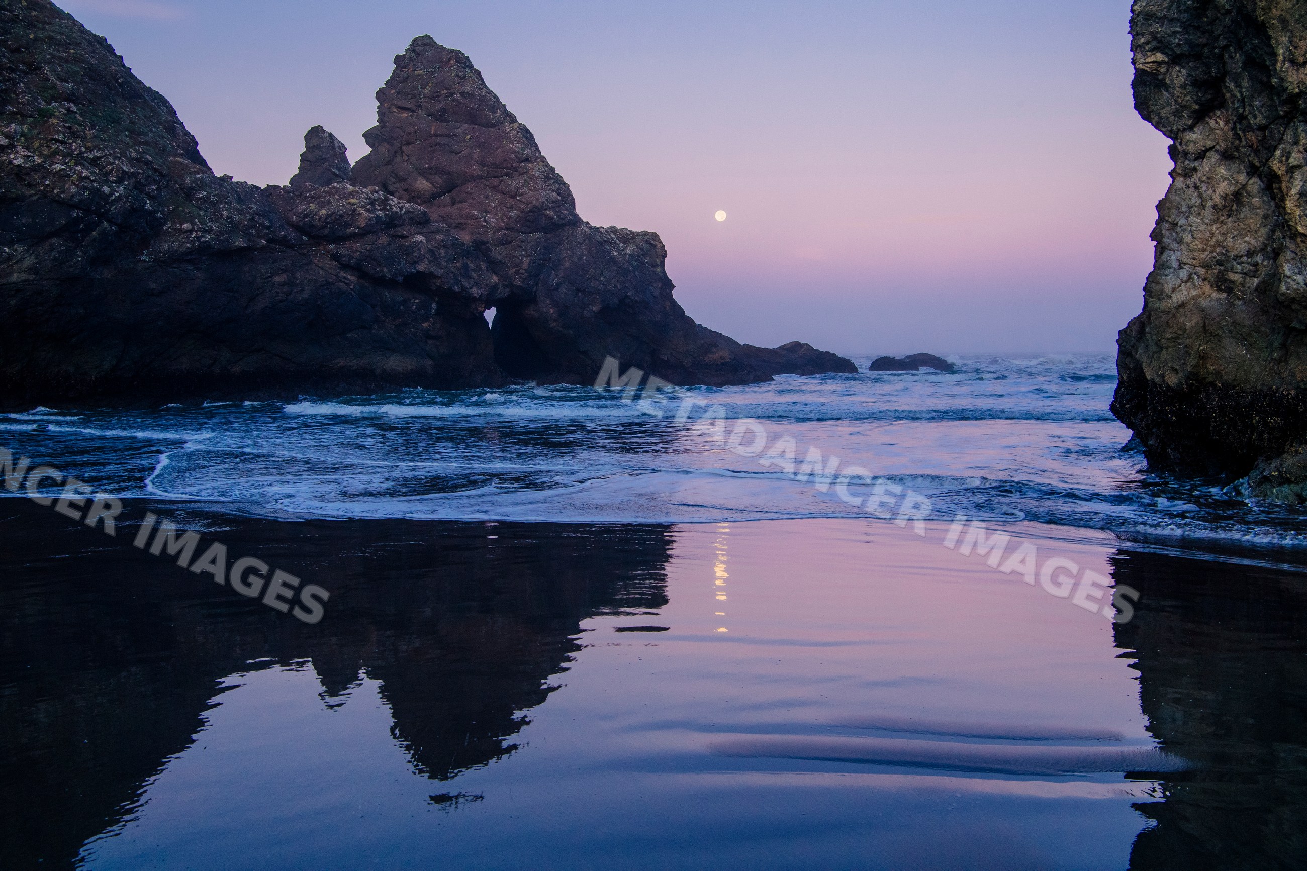 Ocean with rock formations and moon reflected