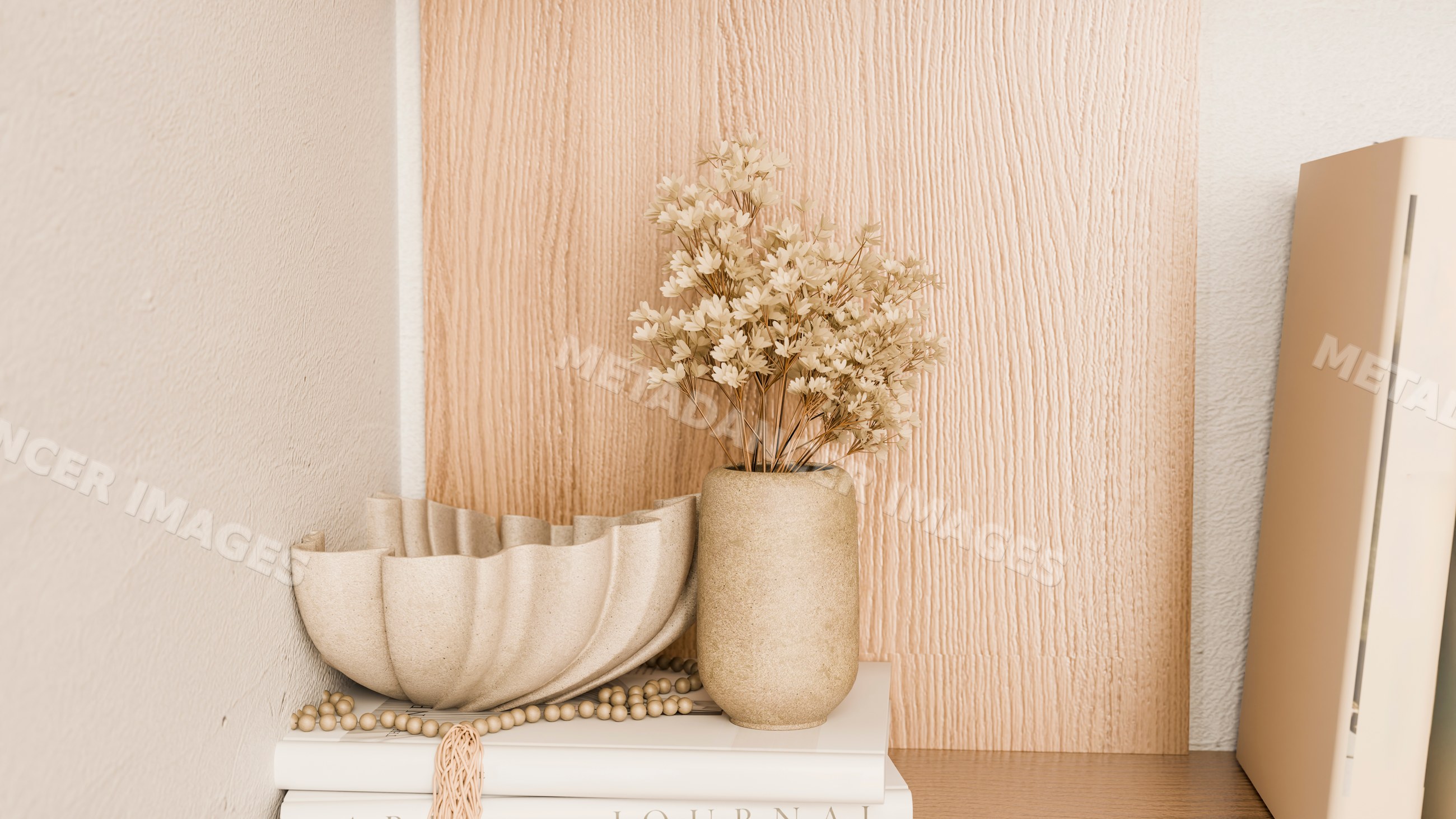 Beige vase with dried flowers and decorative bowl on books