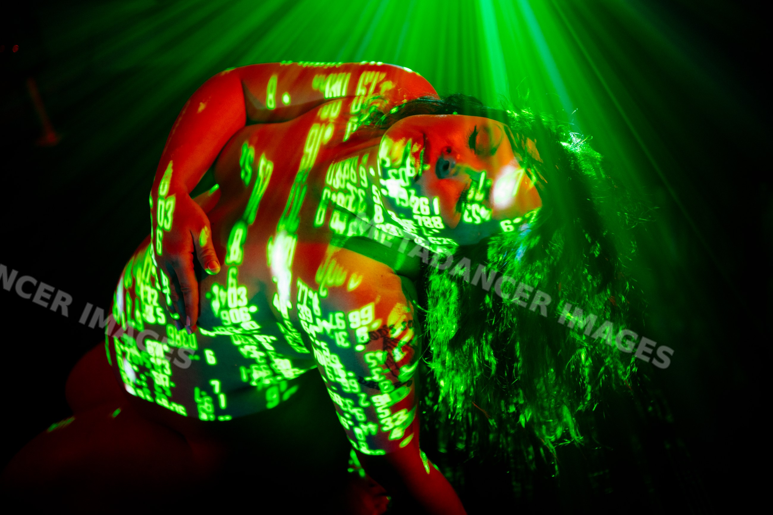 Pregnant white woman illuminated by artistic green numeric projections