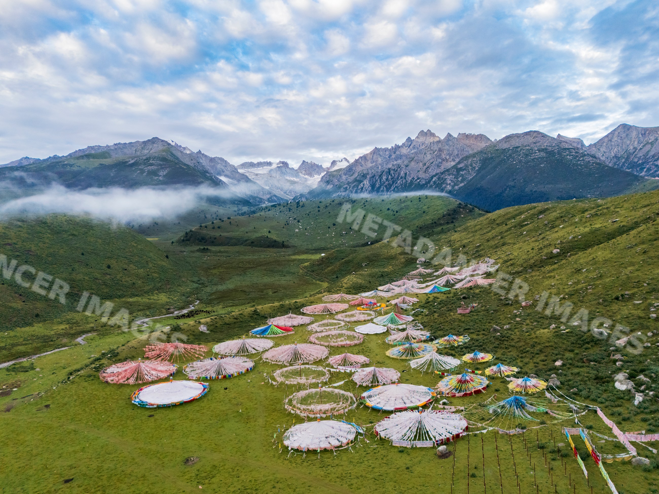 Tibetan buddhist Prayer Flag Circles in grassy valley with mountains