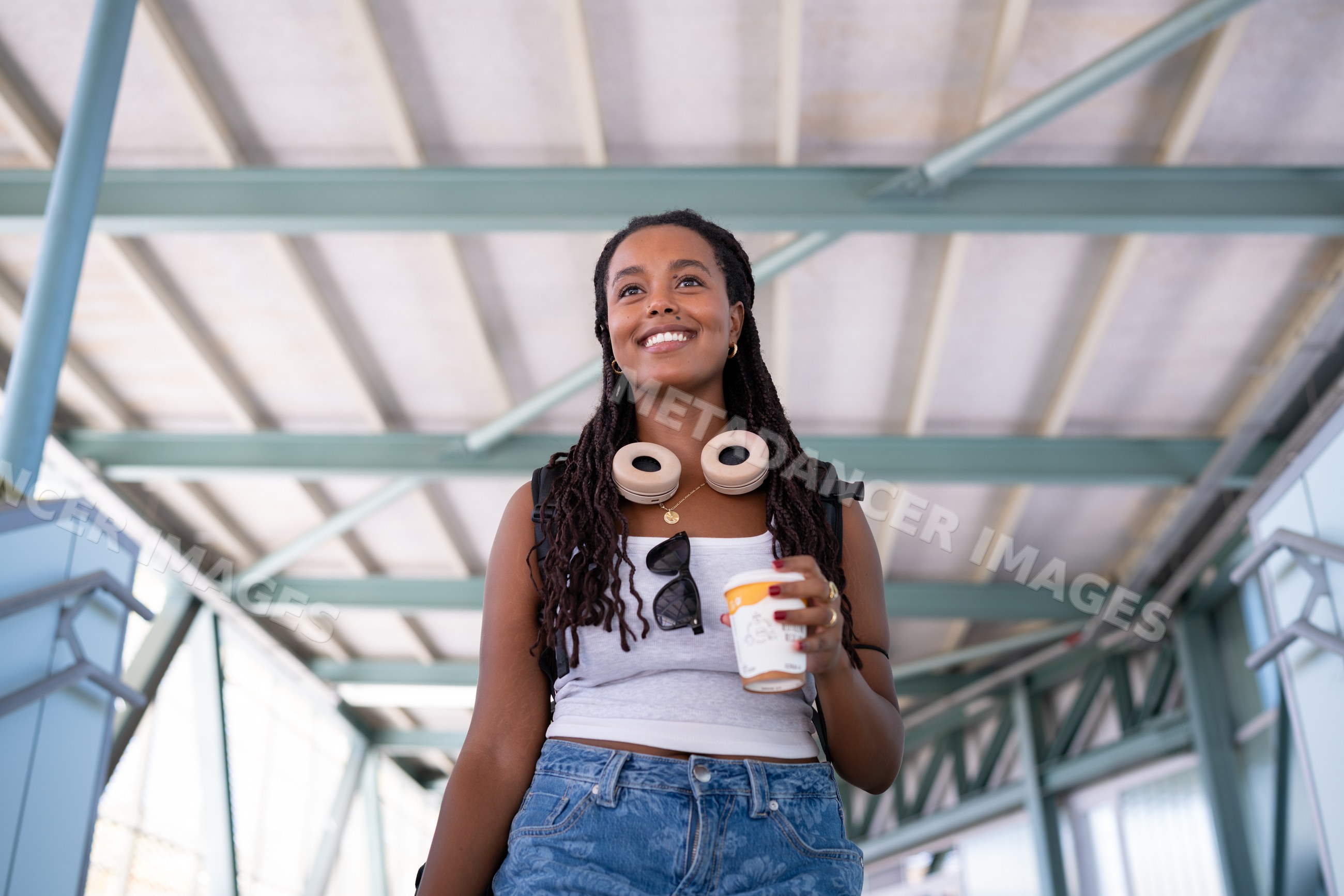 A African American woman holding coffee walks through an indoor