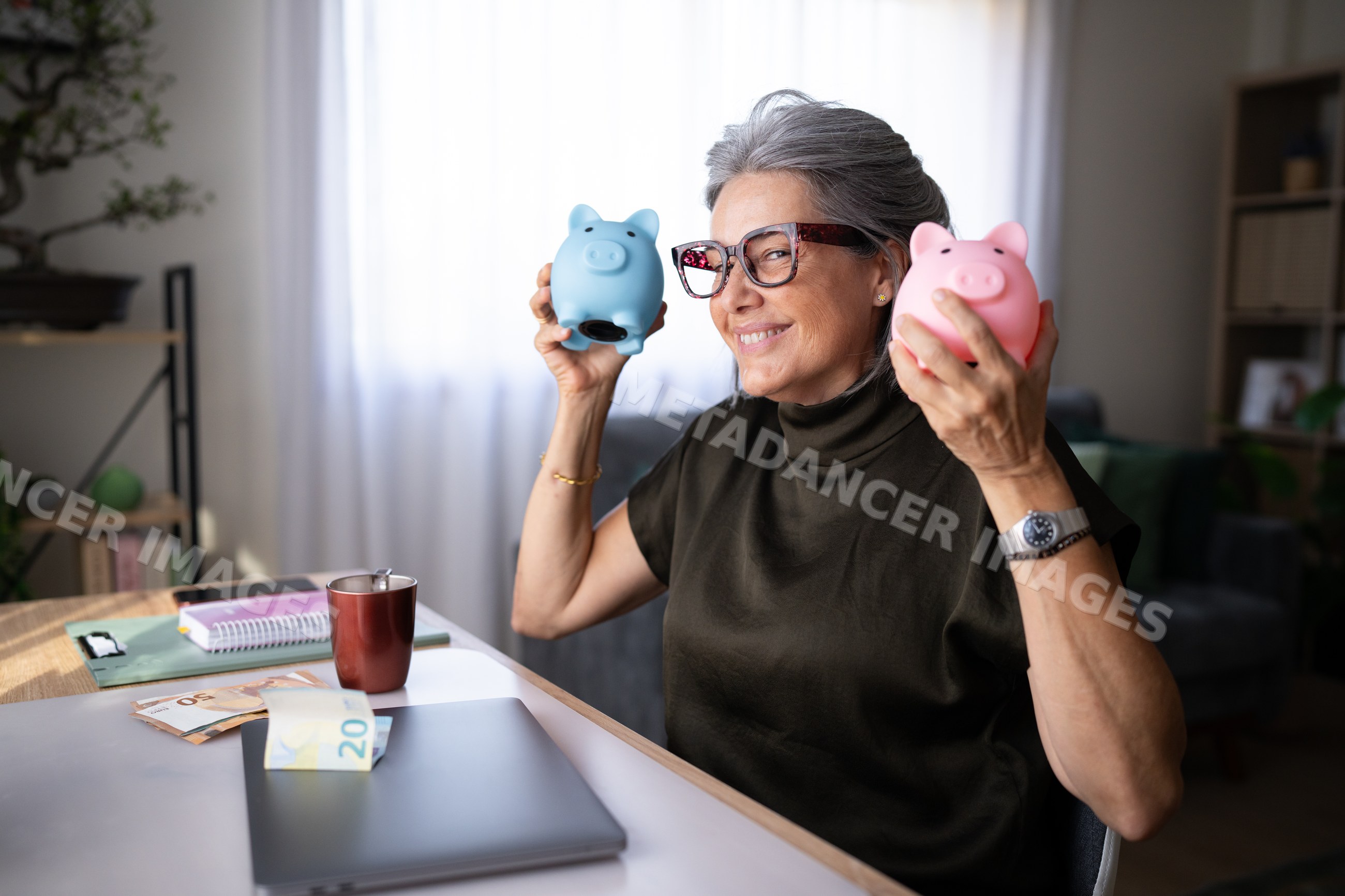 Senior white woman holding piggy banks saving money at home office