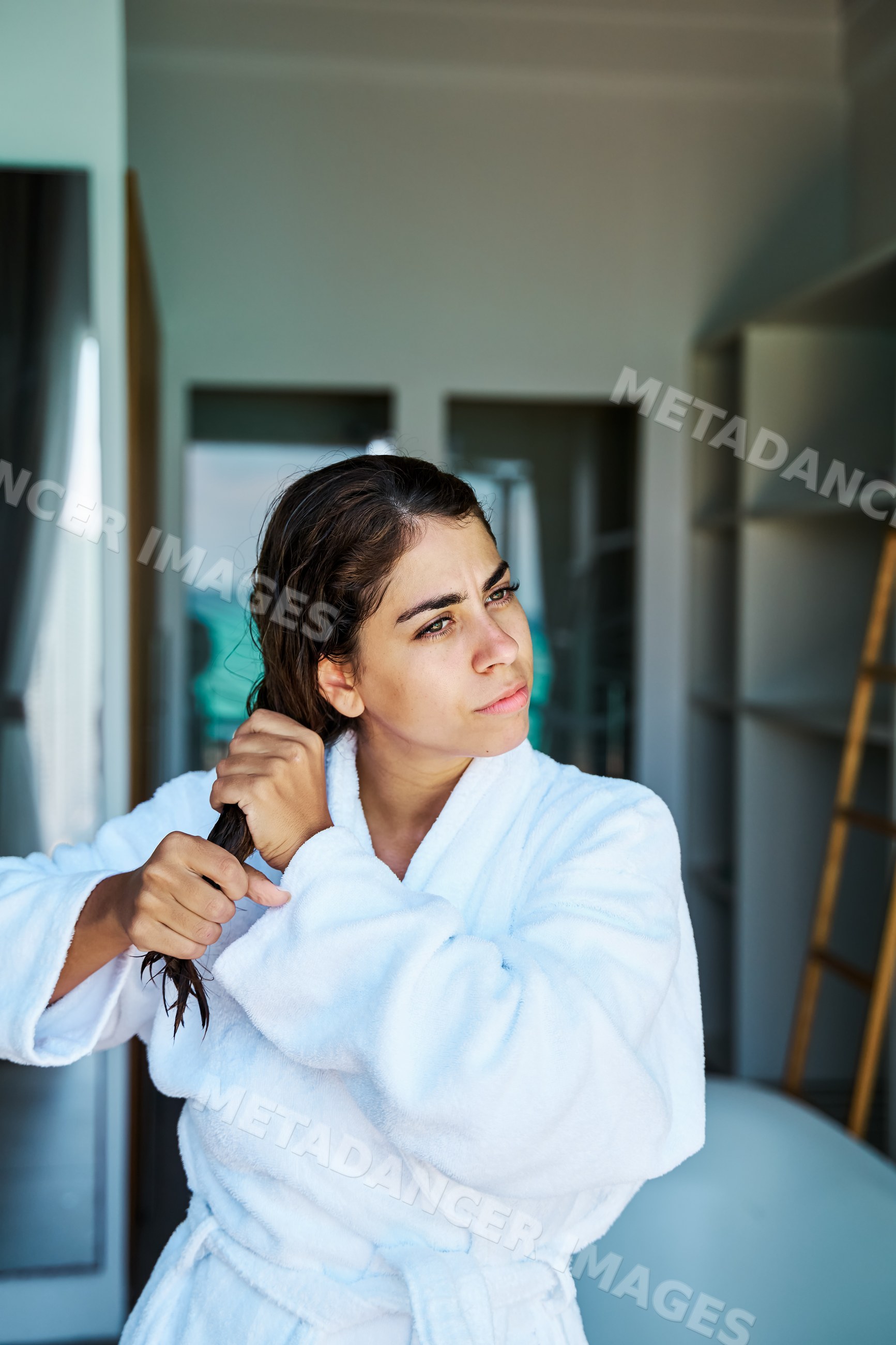A white woman combs her wet hair indoors in a bathroom in a home
