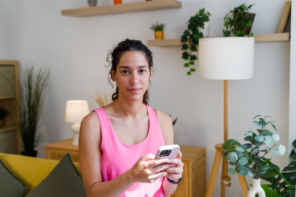 A Hispanic woman uses her smartphone in a modern living room setting