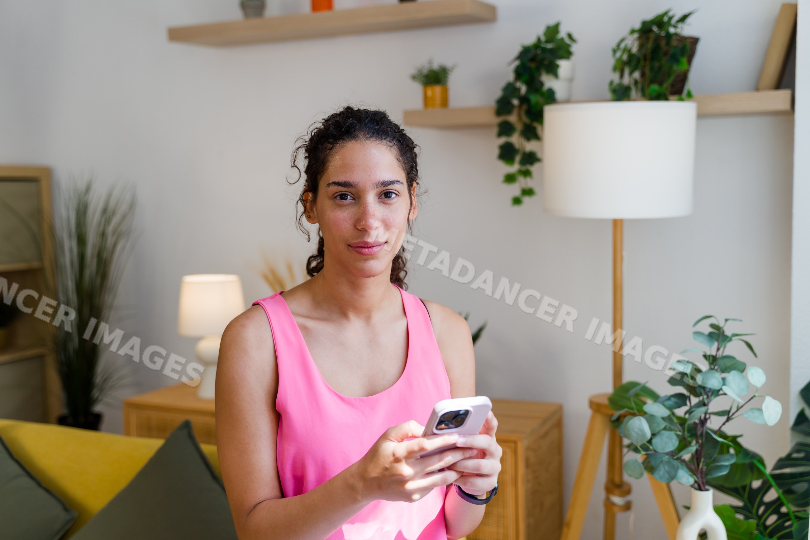 A Hispanic woman uses her smartphone in a modern living room setting